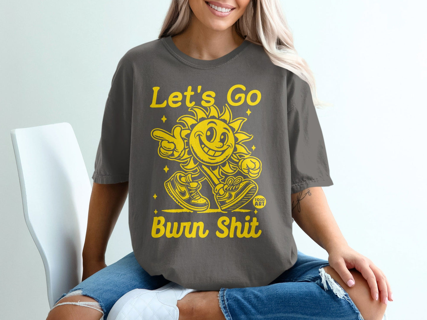 Gray t-shirt with yellow text "Let's Go Burn Shit" and a cartoon sun.
