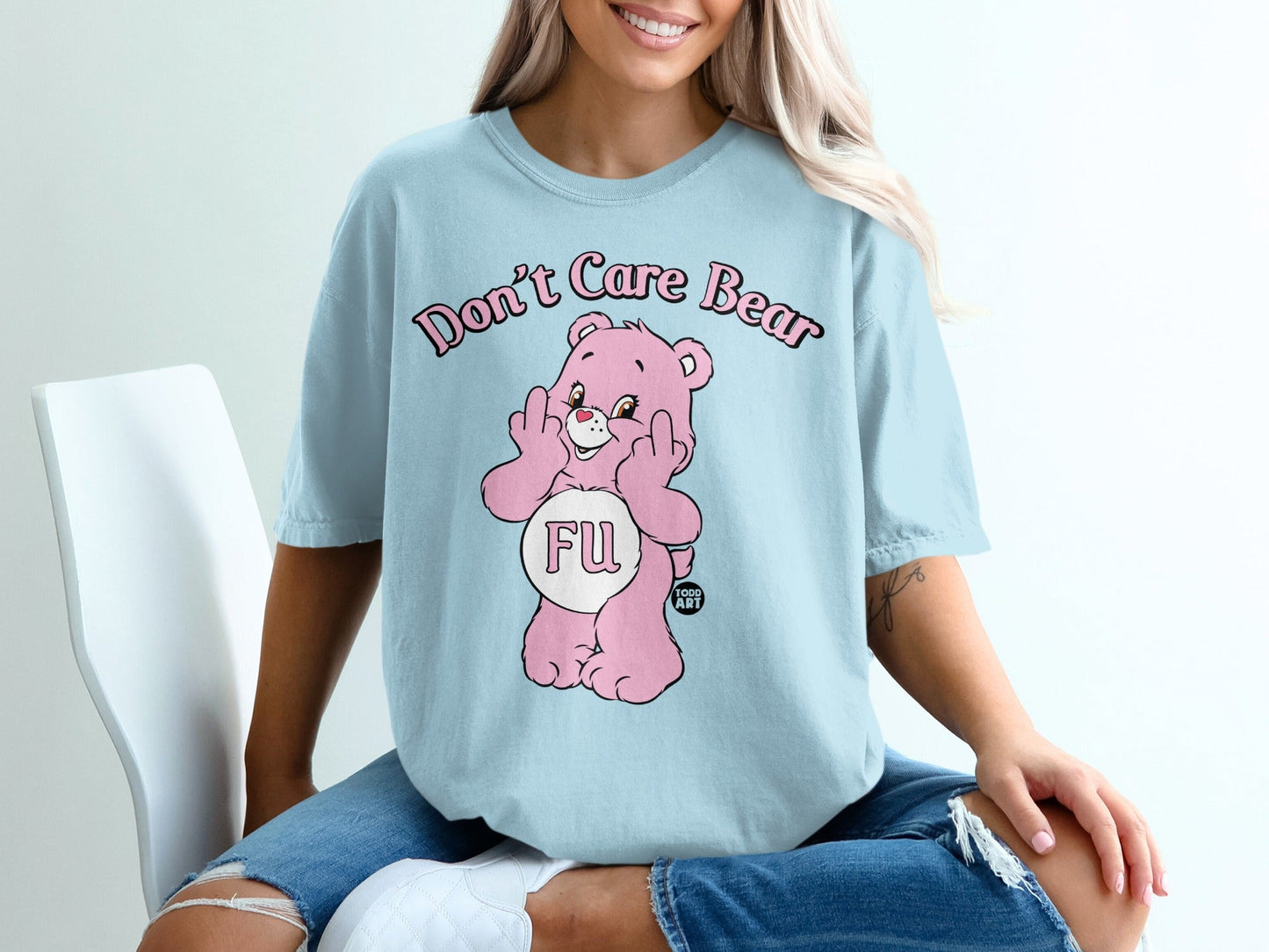 Light blue t-shirt with pink "Don't Care Bear" graphic and middle fingers.