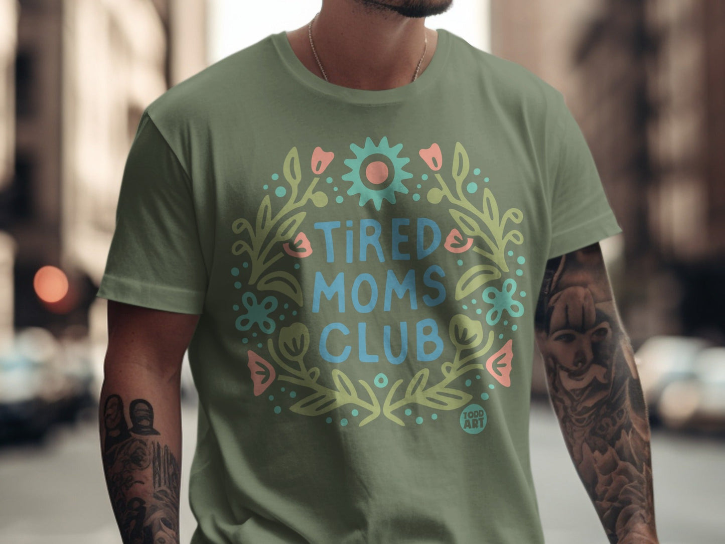 Green t-shirt with "Tired Moms Club" in floral wreath design.