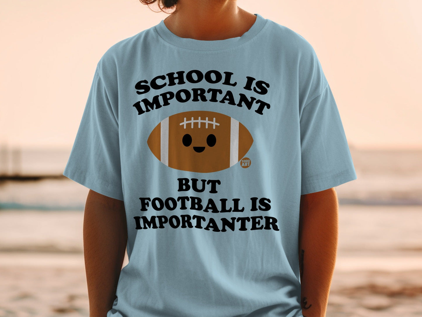 Light blue t-shirt with "SCHOOL IS IMPORTANT BUT FOOTBALL IS IMPORTANTER" and a cartoon football.