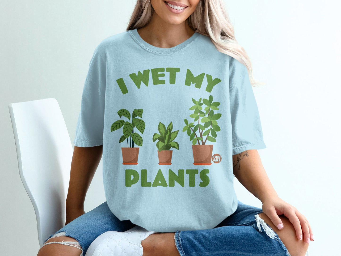 Light blue t-shirt with green text "I WET MY PLANTS" and potted plants graphic.