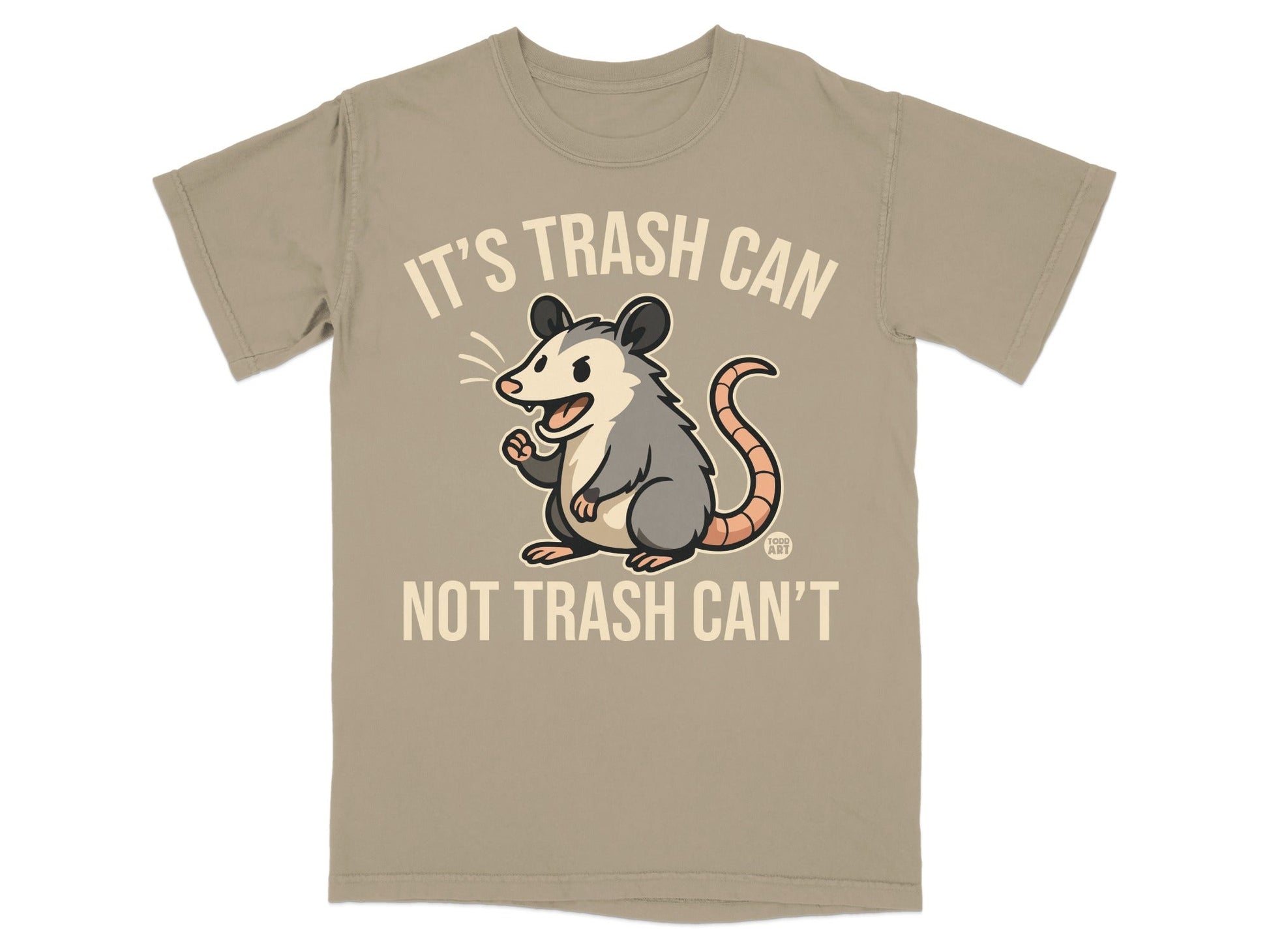 Tan t-shirt with a cartoon opossum and the text "It's Trash Can Not Trash Can't".