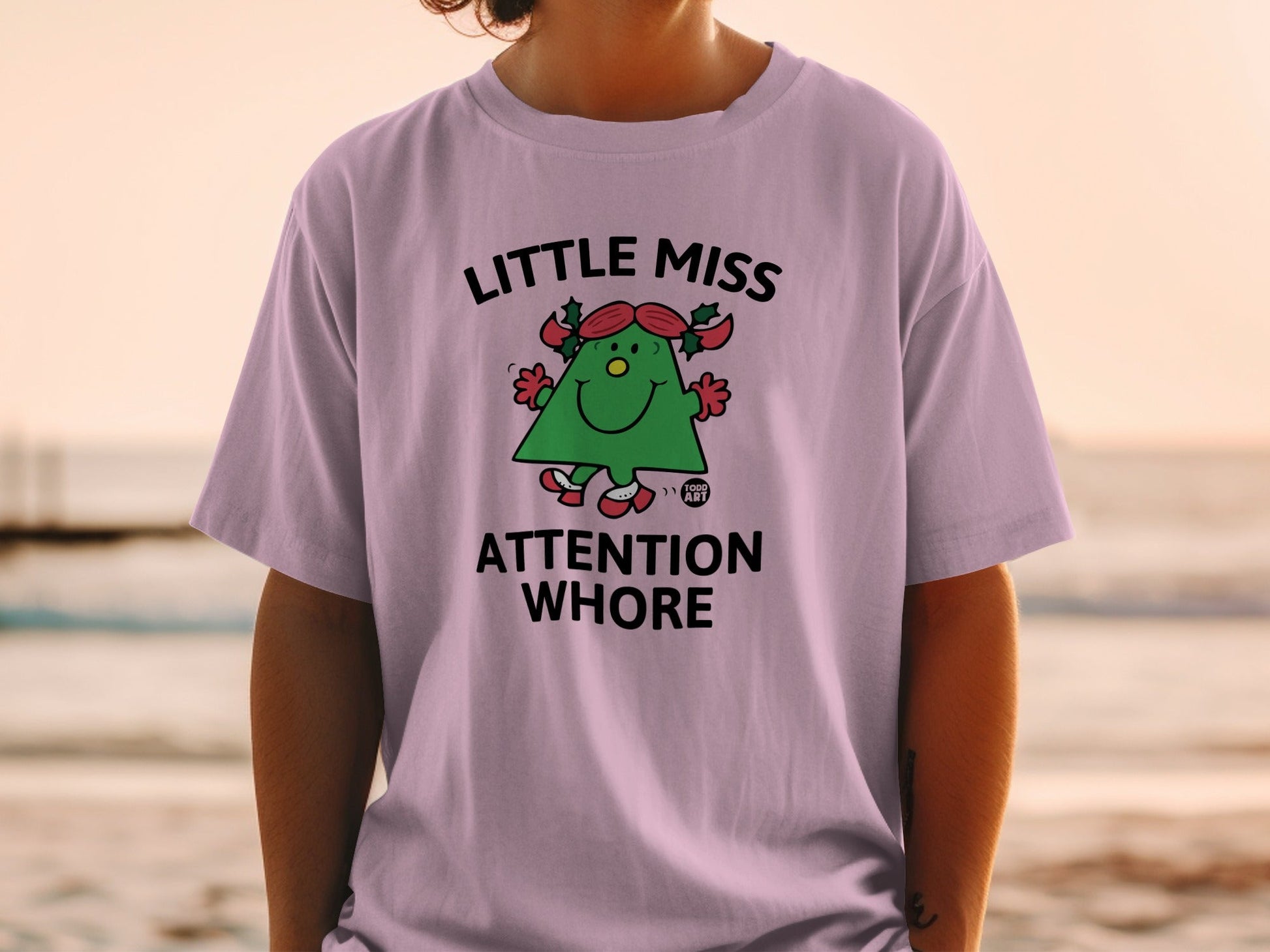 Purple t-shirt with a green cartoon character and "Little Miss Attention Whore" text.