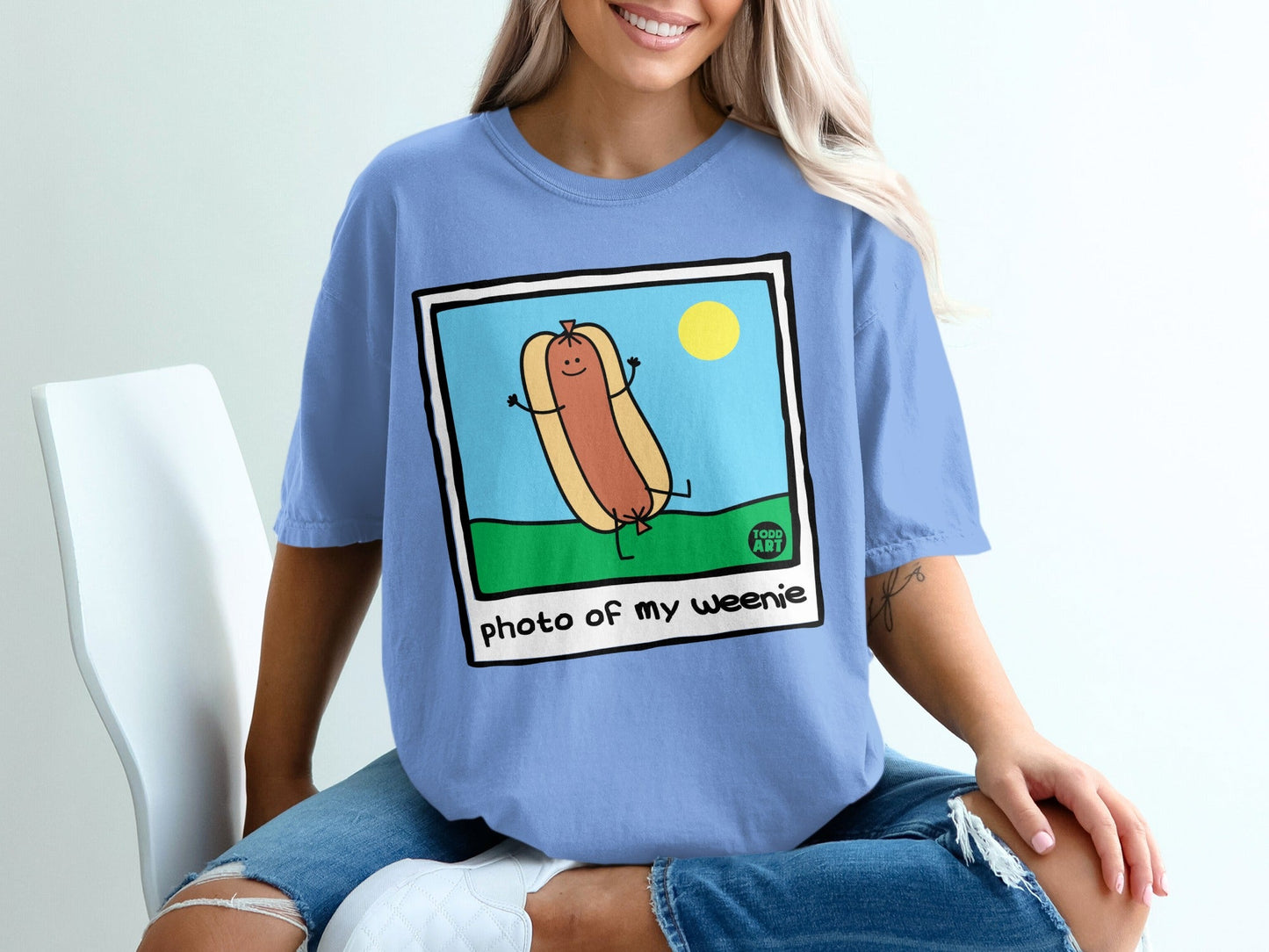 Blue t-shirt with cartoon hot dog saying "photo of my weenie" and a sun.