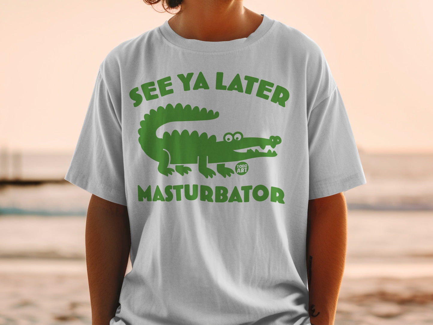 Green alligator graphic with text "SEE YA LATER MASTURBATOR" on white t-shirt.