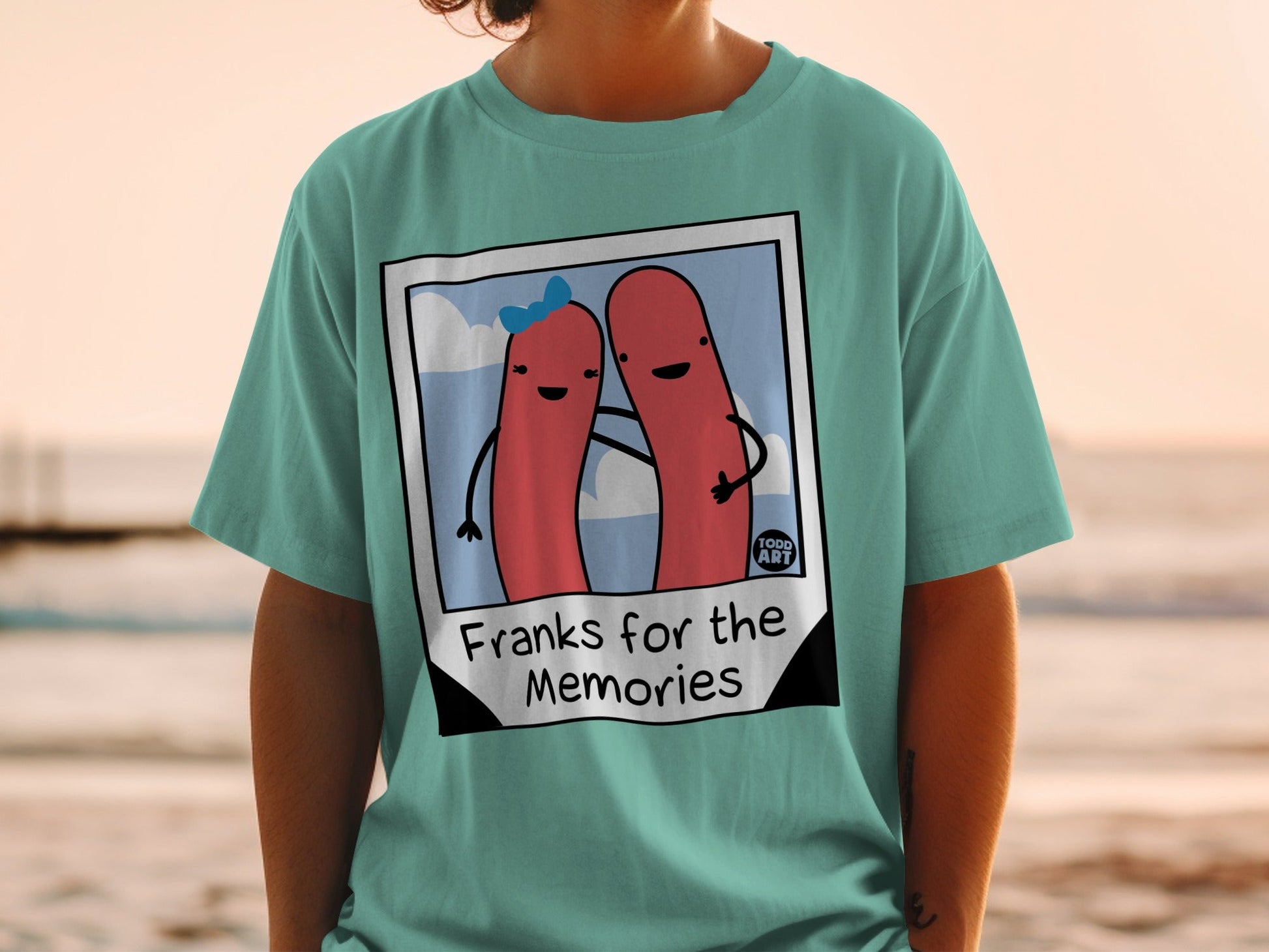 Teal t-shirt with cartoon hot dogs and "Franks for the Memories" text.