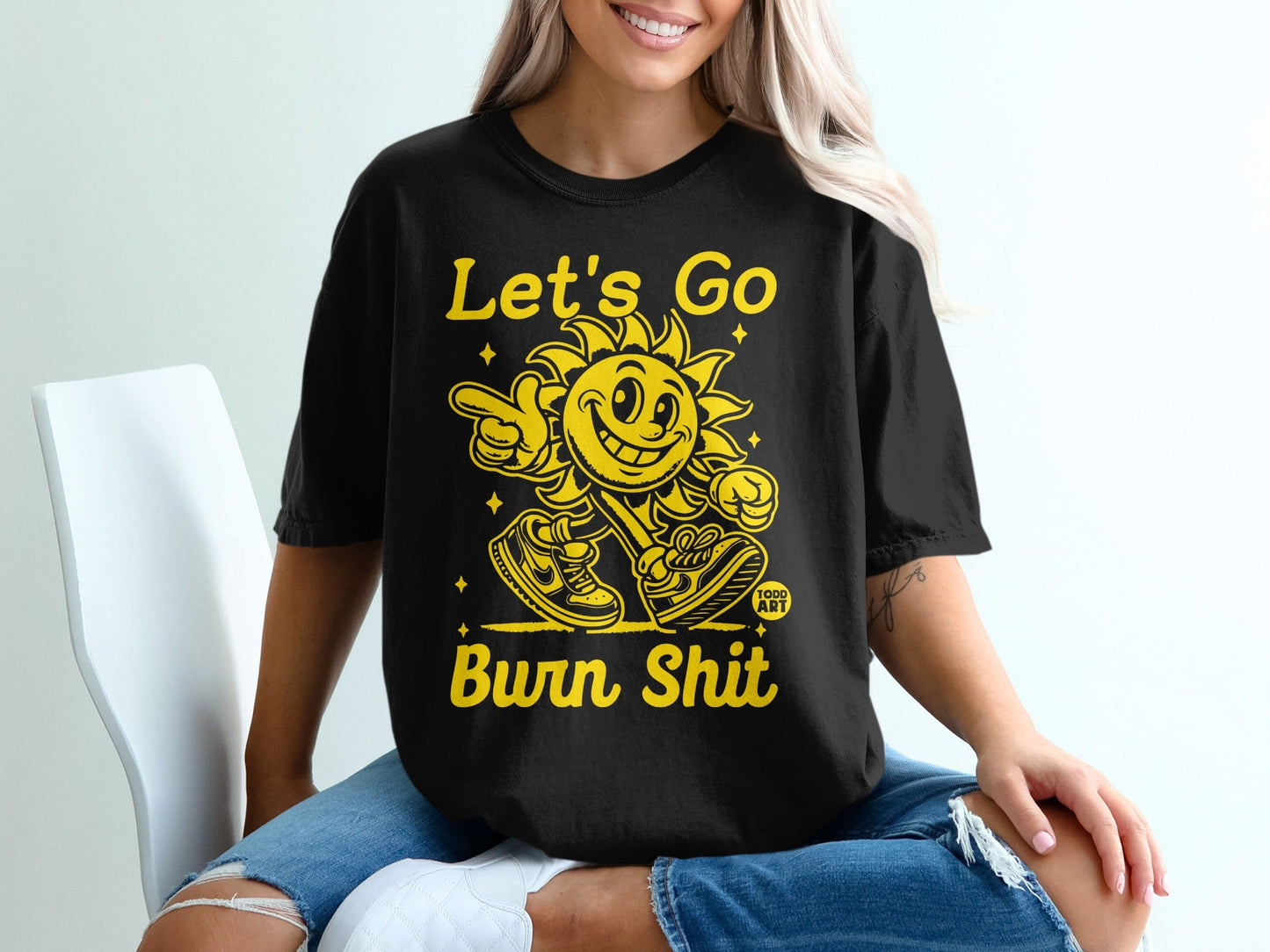 Black t-shirt with yellow "Let's Go Burn Shit" sun graphic.
