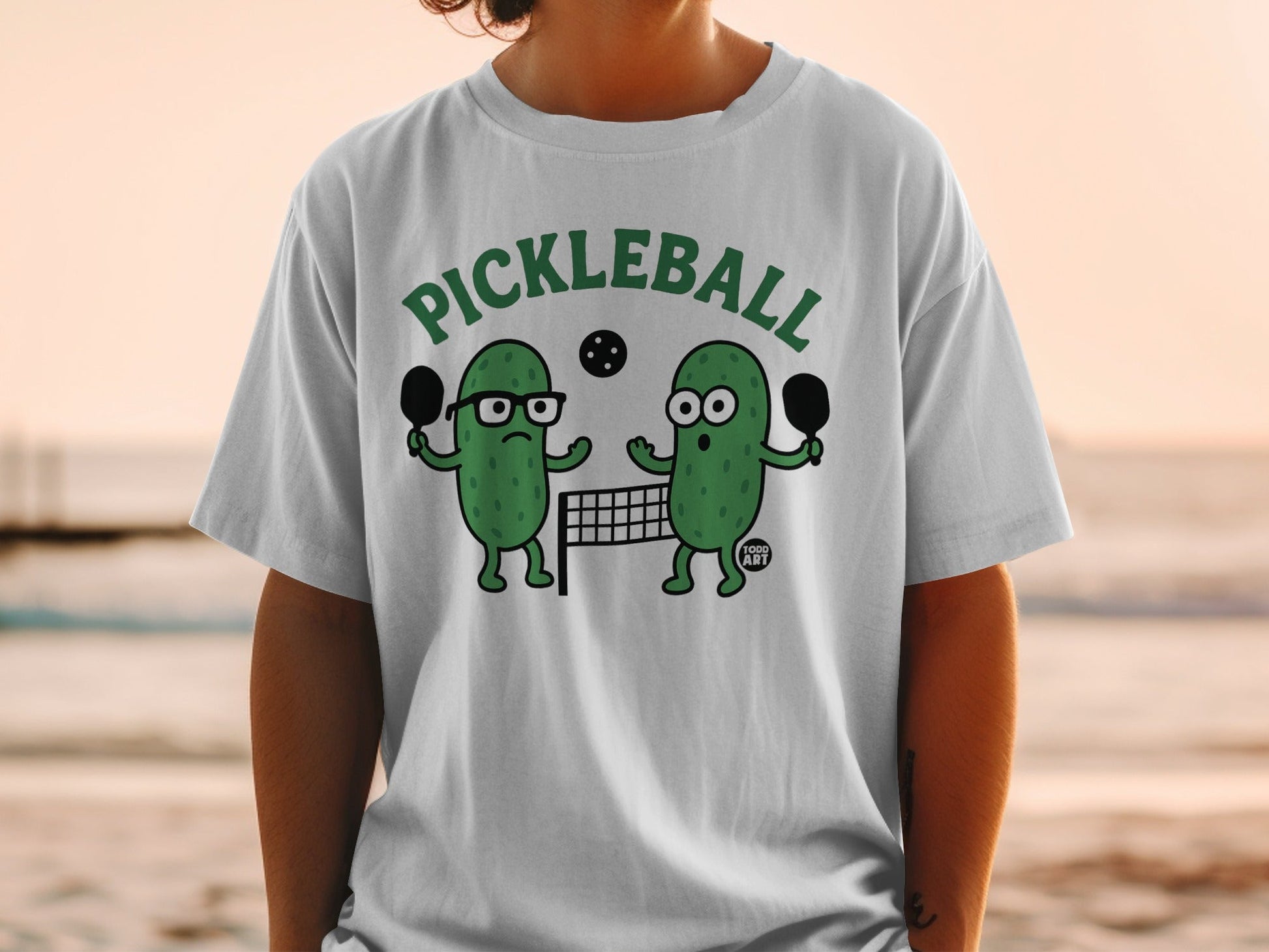 Two cartoon pickles play pickleball in front of a net.
