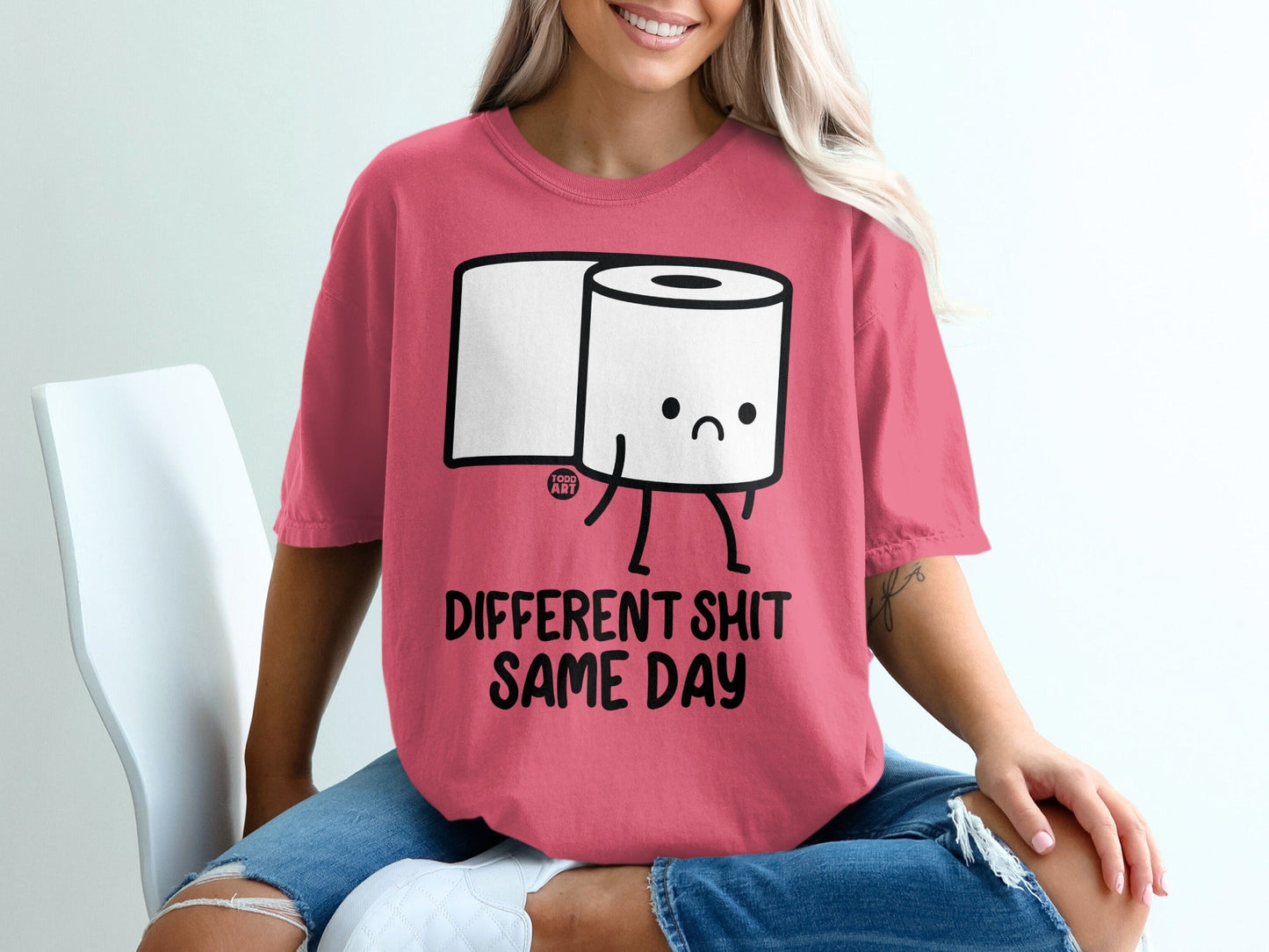 Pink t-shirt with cartoon toilet paper and text "DIFFERENT SHIT SAME DAY".