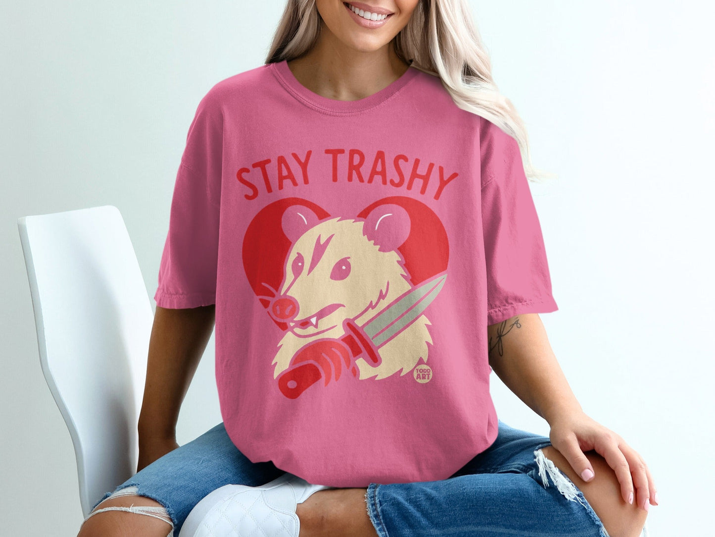 Pink t-shirt with "Stay Trashy" text and a possum holding a knife.