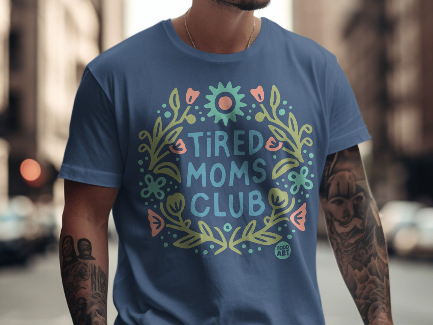 Blue t-shirt with "Tired Moms Club" text and floral wreath.