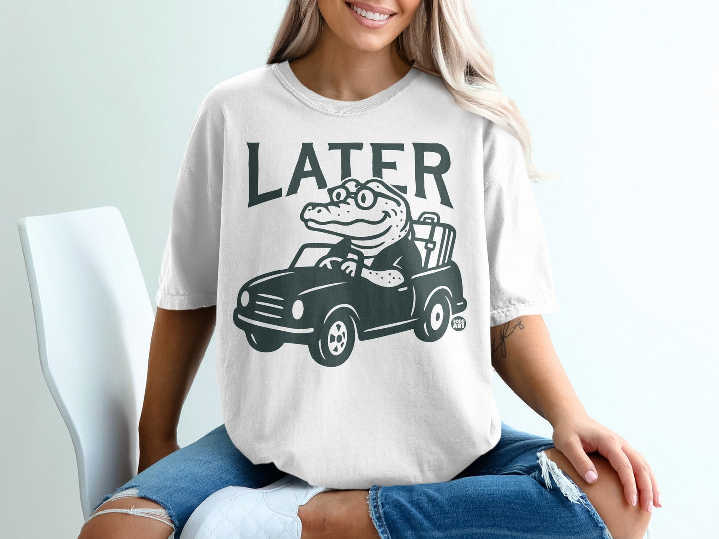 White t-shirt with a cartoon alligator driving a car, text "LATER" above.