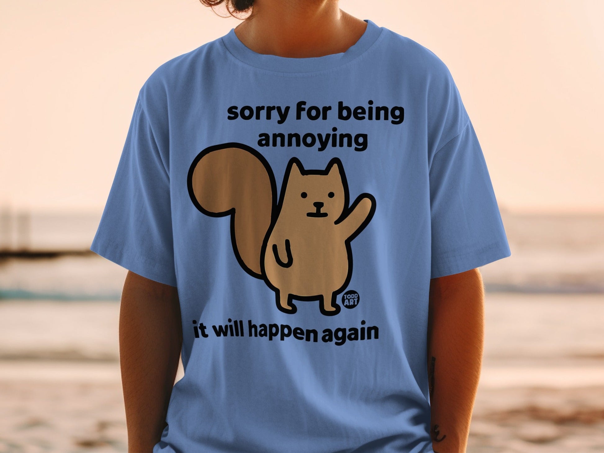 Blue t-shirt with a cartoon squirrel saying "sorry for being annoying it will happen again."