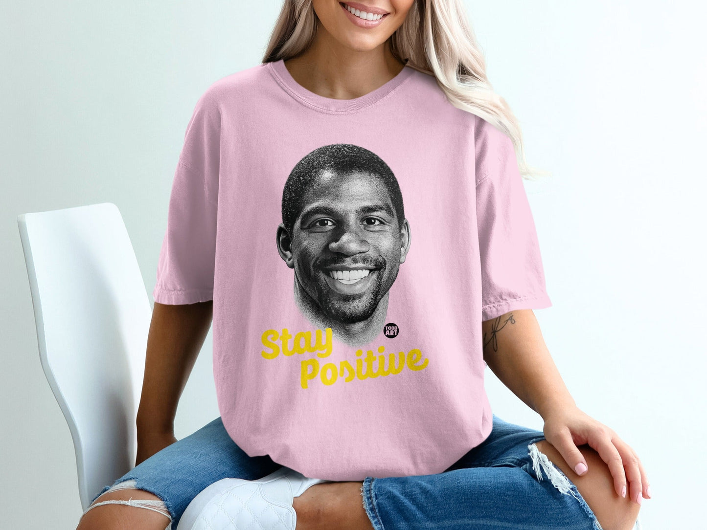 Pink t-shirt with Magic Johnson's smiling portrait and "Stay Positive" text.