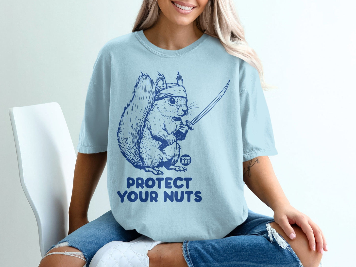 Light blue t-shirt with navy squirrel graphic and "PROTECT YOUR NUTS" text.