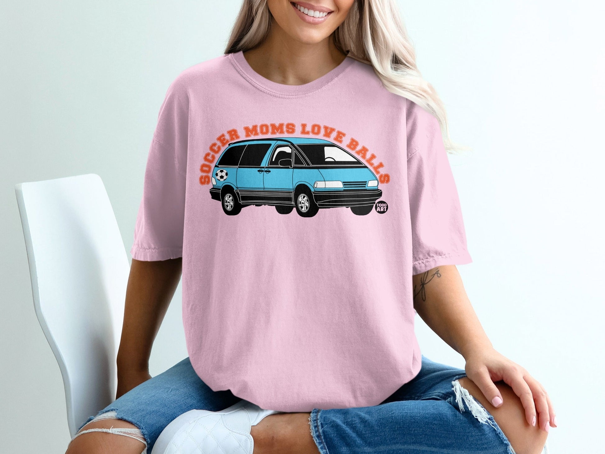 Pink t-shirt with graphic of blue minivan and text "Soccer Moms Love Balls".