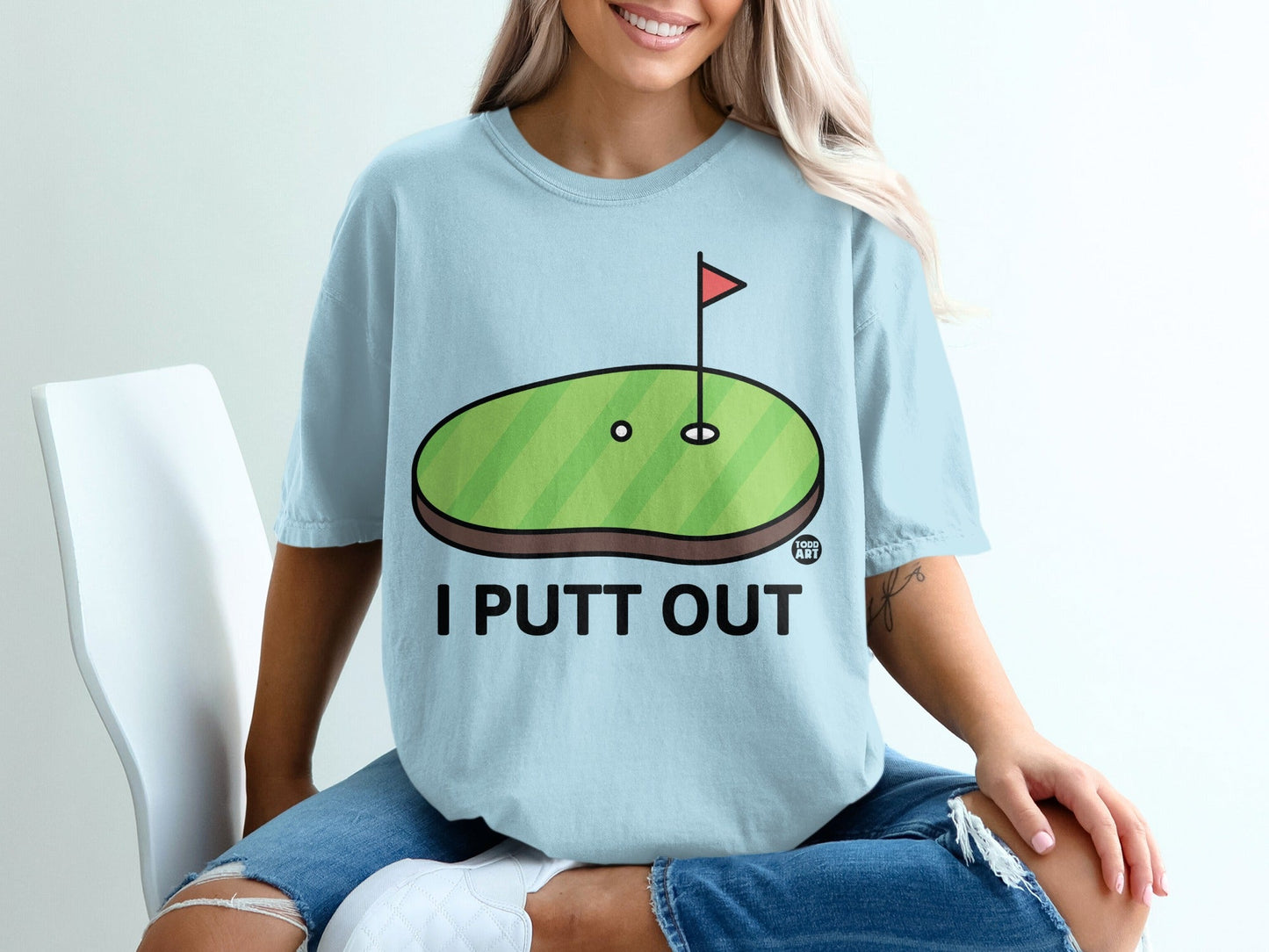 Light blue t-shirt with "I PUTT OUT" text and a golf hole design.