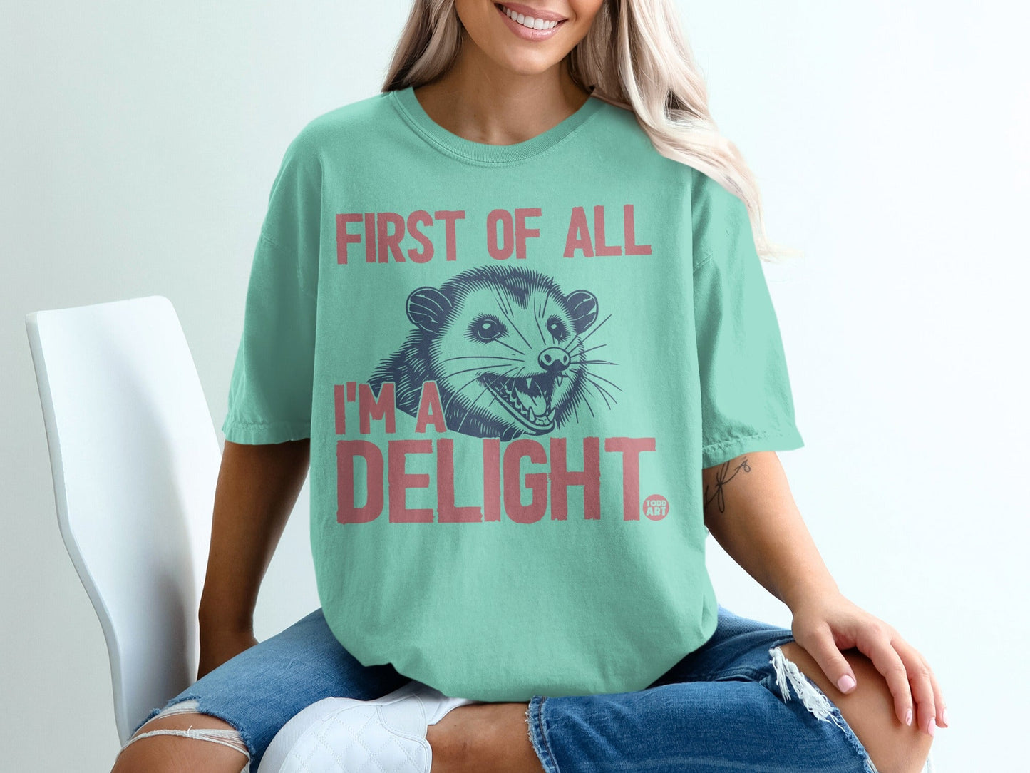 Mint green t-shirt with a possum and "First of all I'm a delight" text.