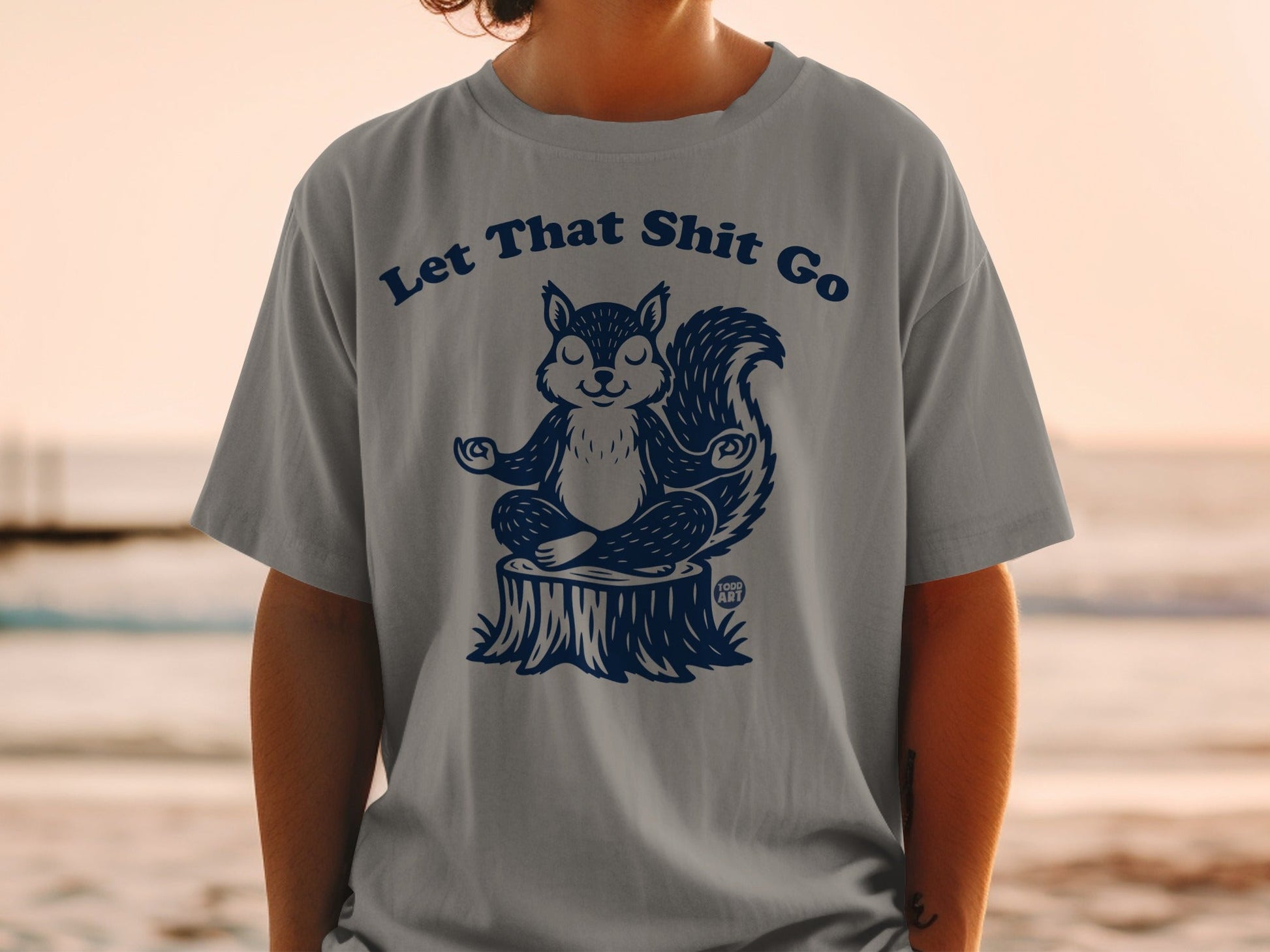 Squirrel meditating on a tree stump wearing shirt with text "Let That Sh*t Go".