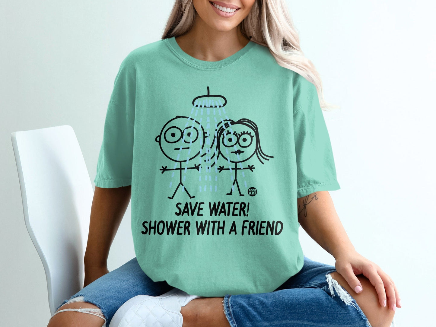 Mint t-shirt with cartoon figures under a shower and text "SAVE WATER! SHOWER WITH A FRIEND!".