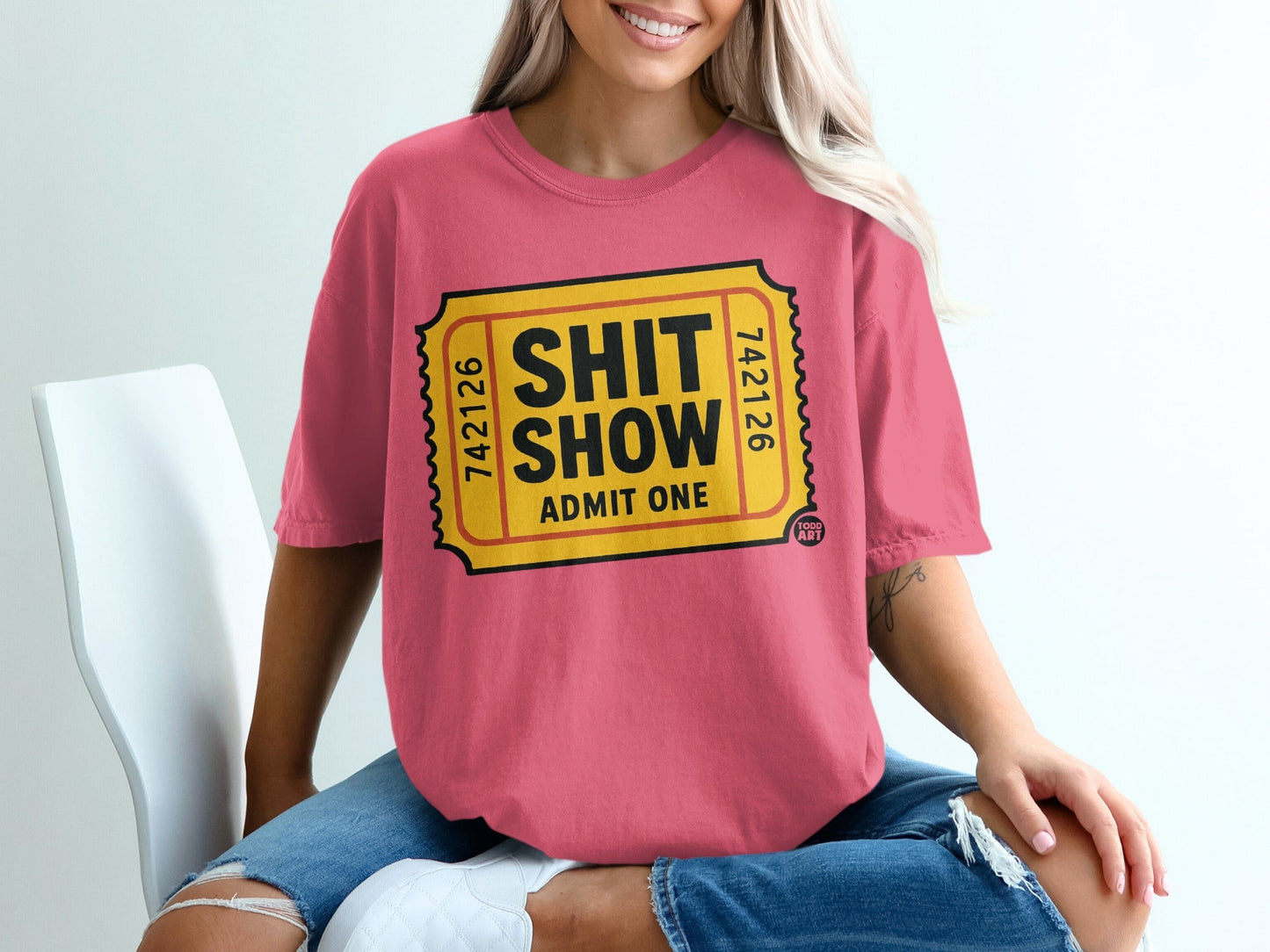 Pink t-shirt with a yellow ticket graphic that reads "SHIT SHOW ADMIT ONE."