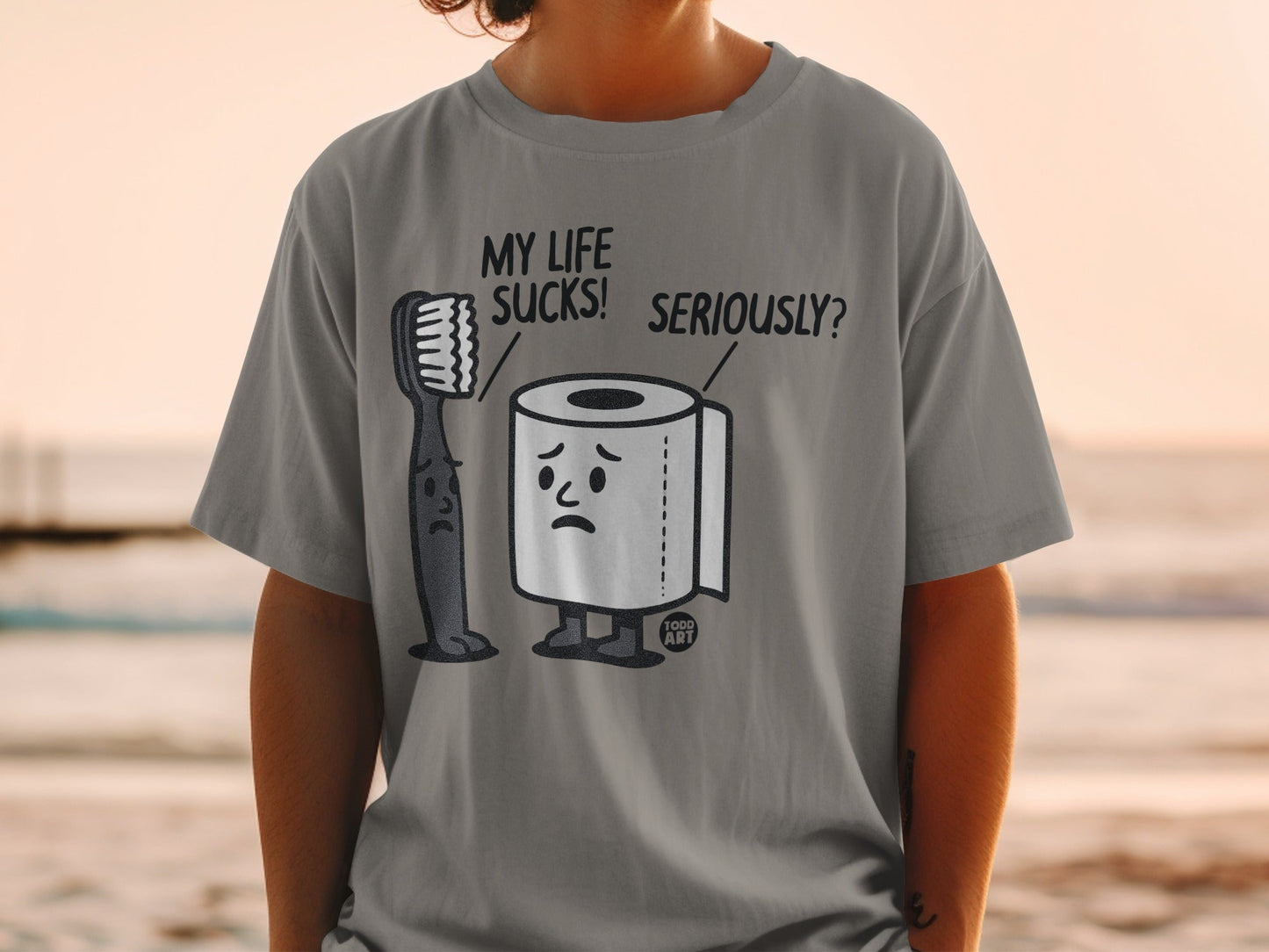 Gray t-shirt with cartoon toothbrush and toilet paper characters that read "MY LIFE SUCKS! SERIOUSLY?"