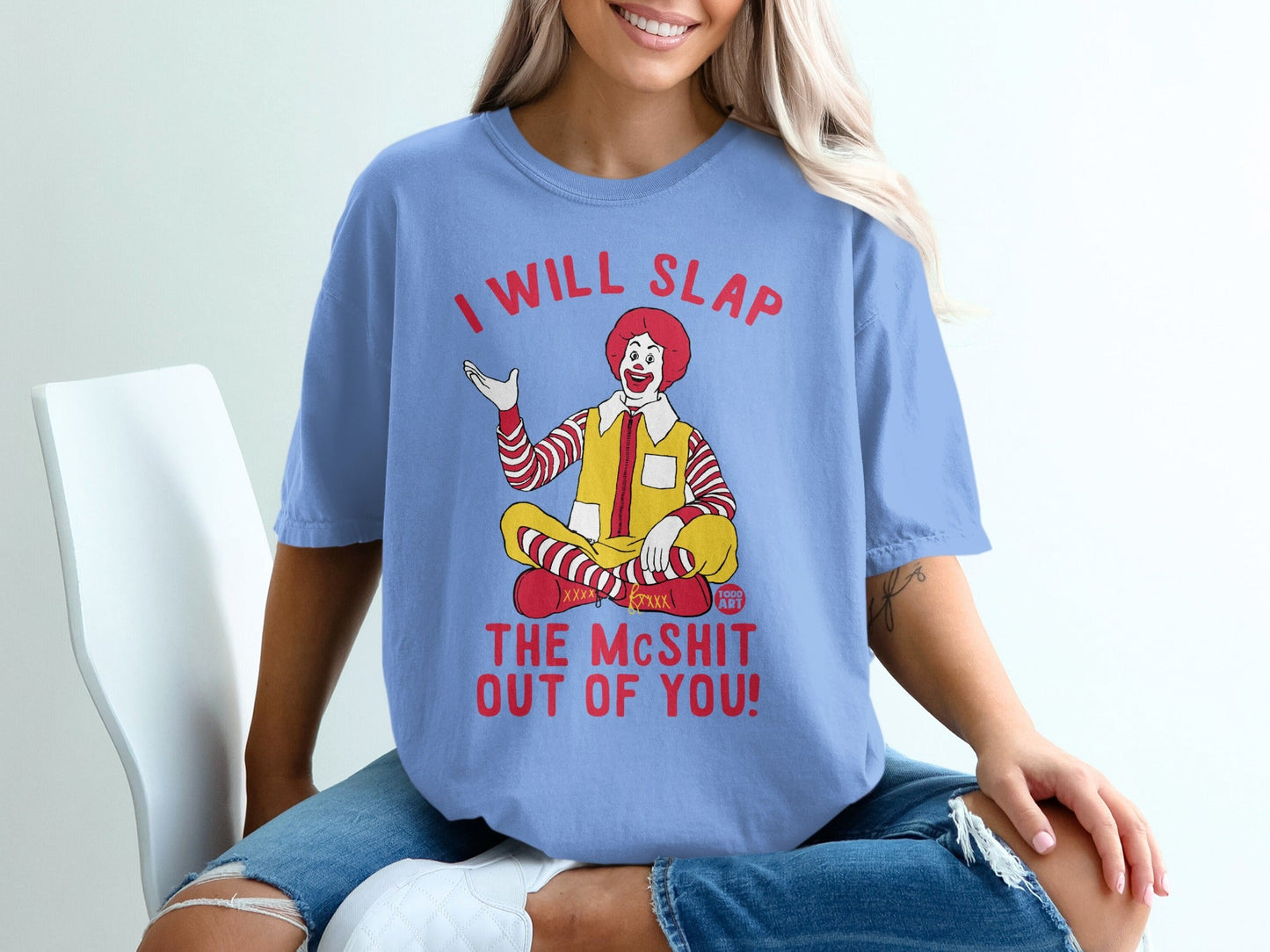 Ronald McDonald sitting cross-legged on a blue t-shirt with text.