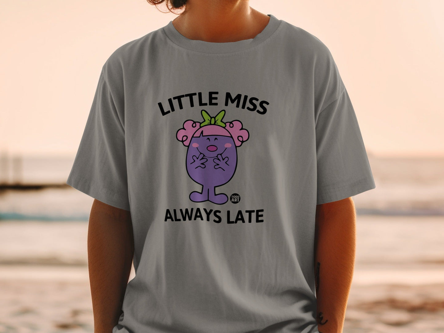 Little Miss Always Late character on a grey t-shirt.
