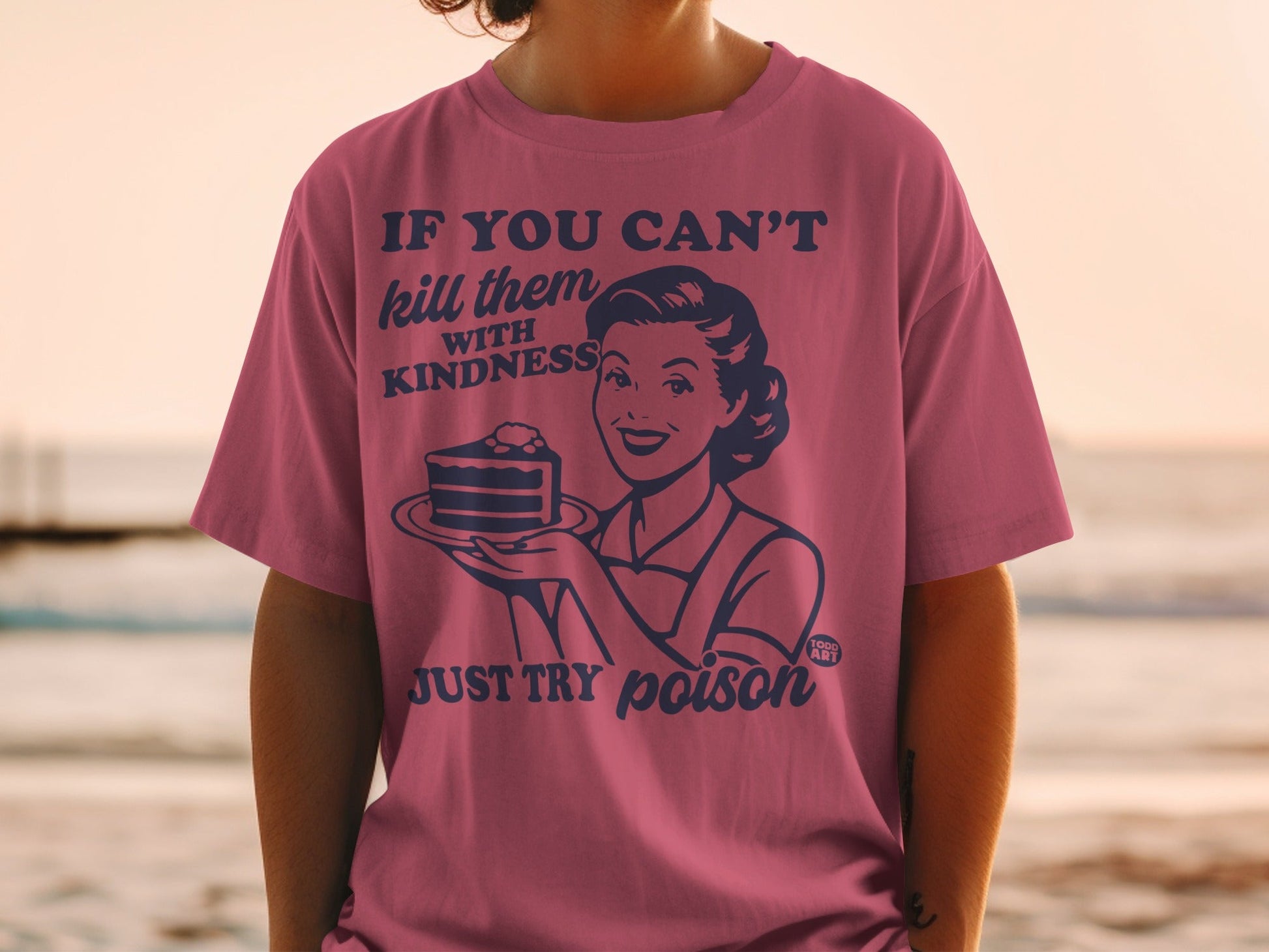 Woman in pink shirt holds a cake with text "If you can't kill them with kindness, just try poison."