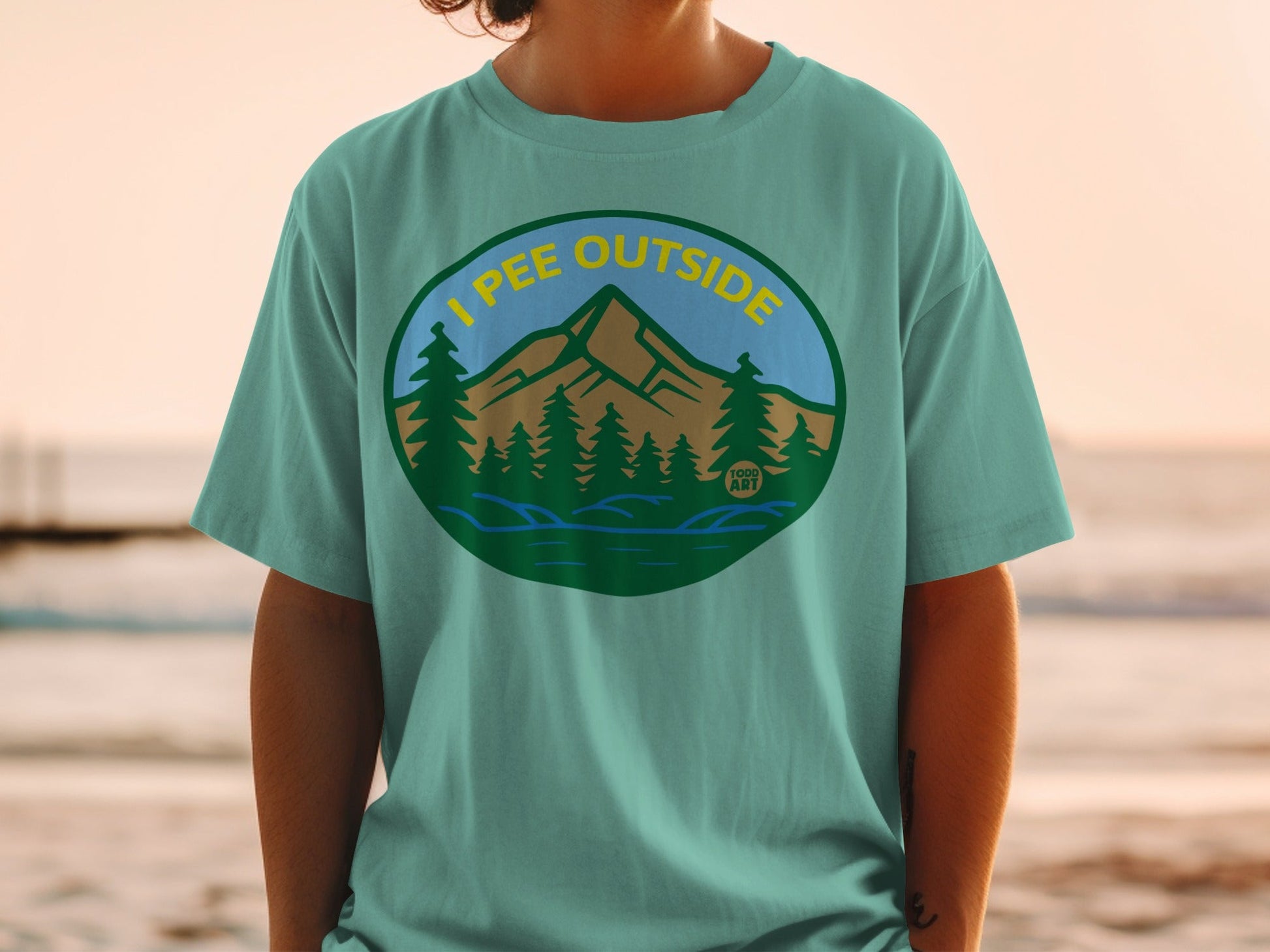 Green t-shirt with "I PEE OUTSIDE" text and mountain landscape graphic.