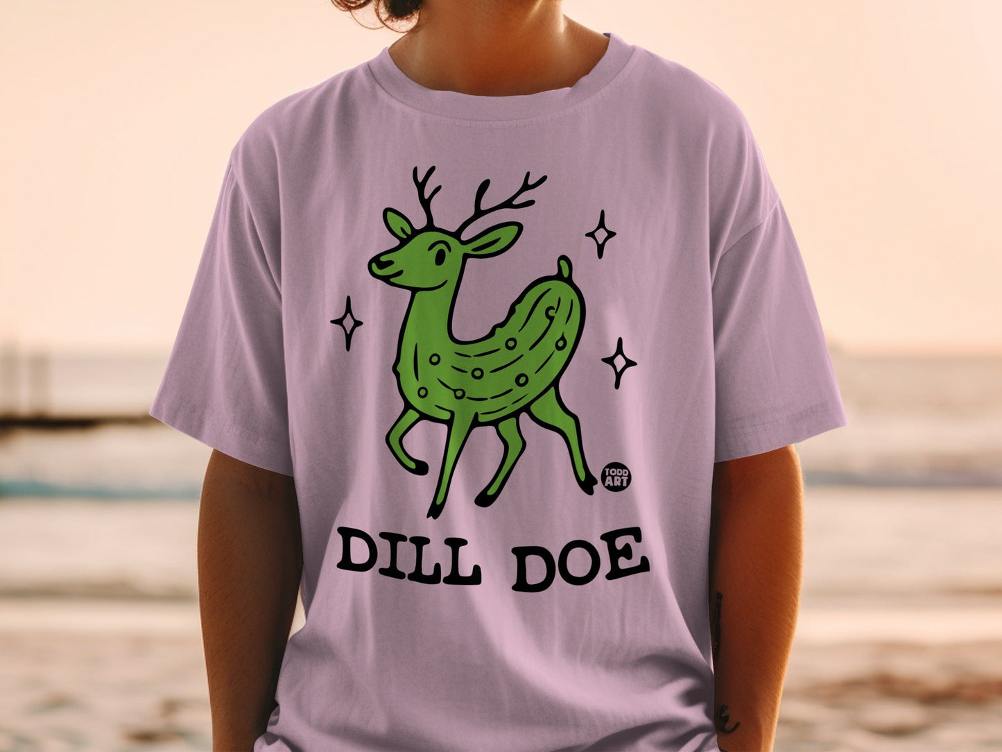 Green pickle deer with antlers on a lilac t-shirt, "Dill Doe" text.