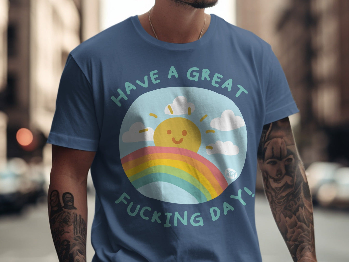 Blue t-shirt with smiling sun, rainbow, and text "Have a great fucking day!".