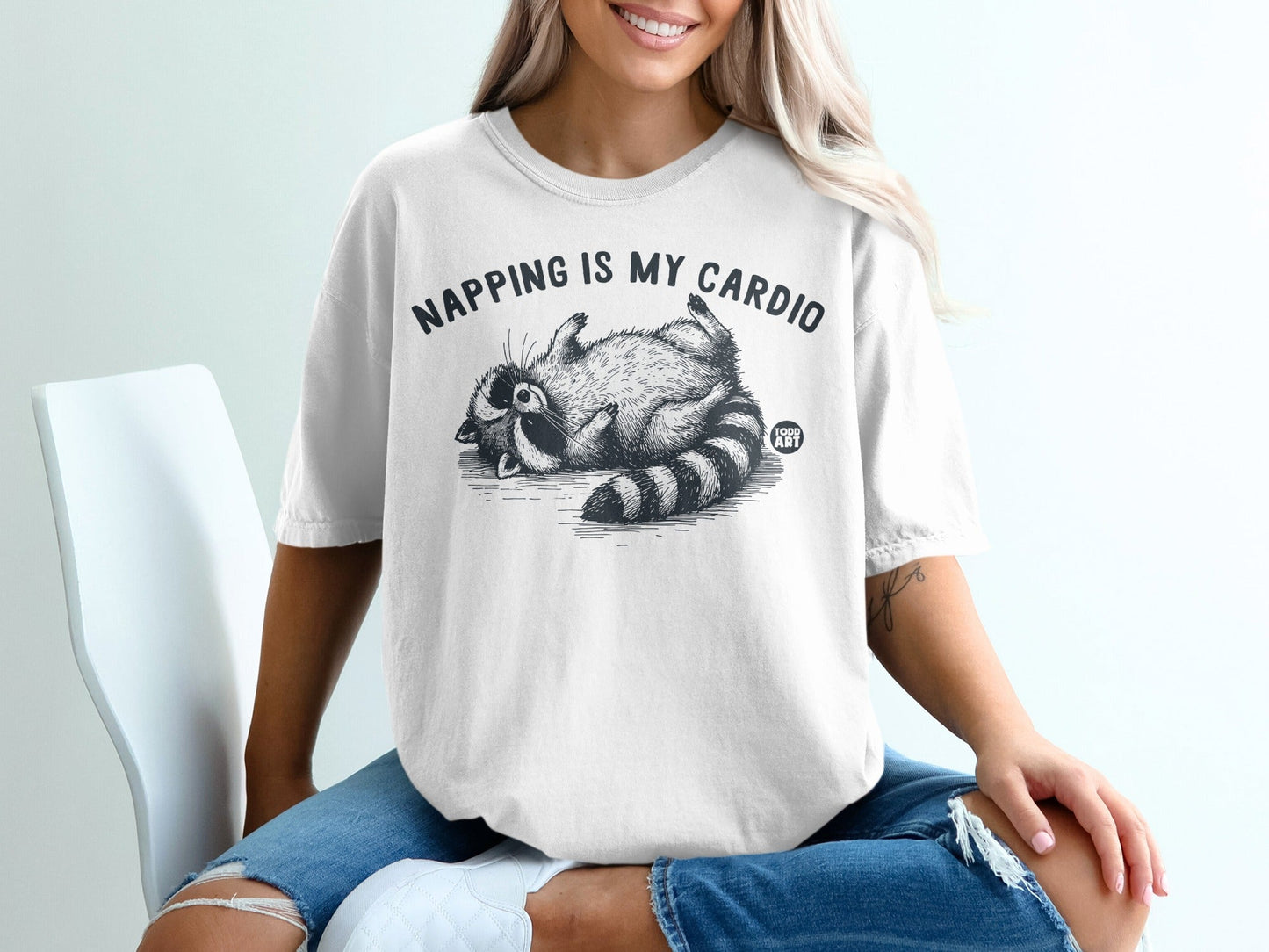T-shirt with raccoon illustration and text "Napping is my cardio".