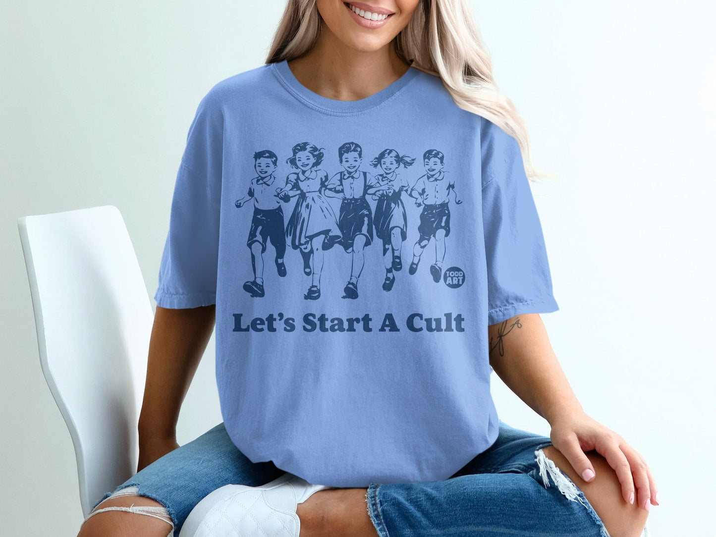 Light blue t-shirt with illustration of children running and text "Let's Start A Cult".
