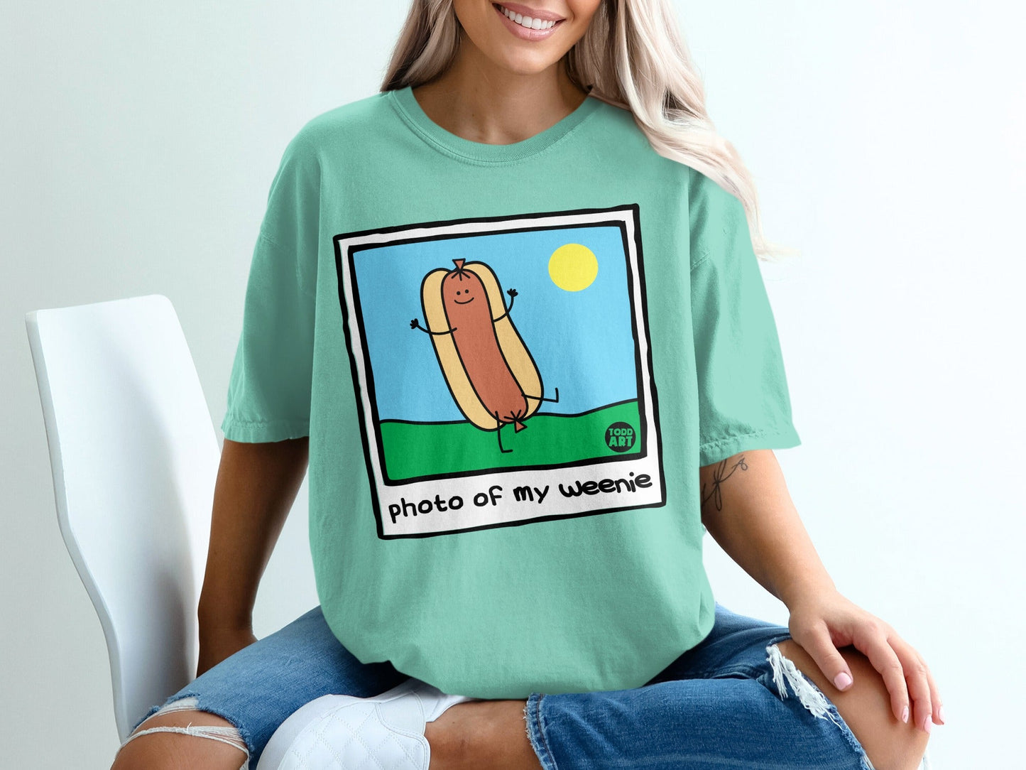 Cartoon hot dog with arms raised, smiling in a sunny field.