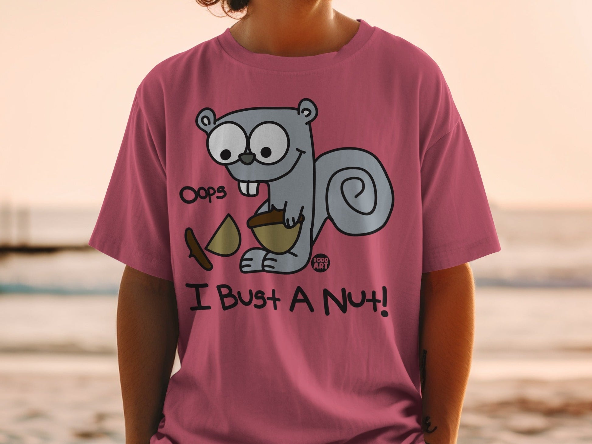 Pink t-shirt with cartoon squirrel saying "Oops, I bust a nut!"