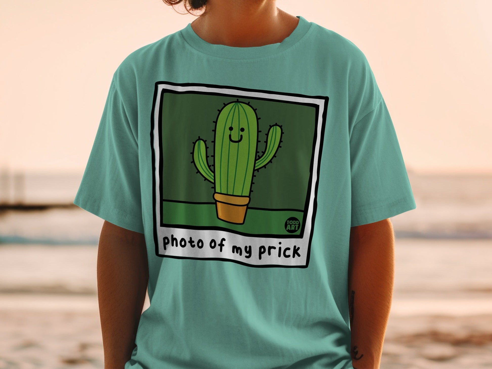 Teal t-shirt with a cartoon cactus illustration and "photo of my prick" text.