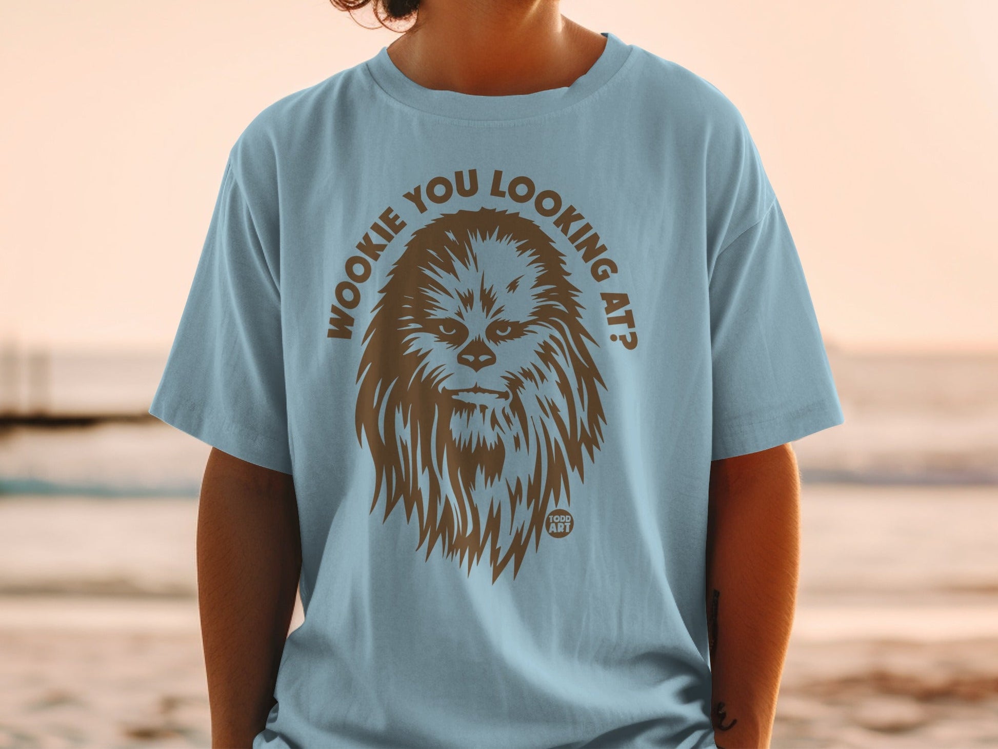 Light blue t-shirt with brown Chewbacca graphic and text "Wookiee you looking at?".