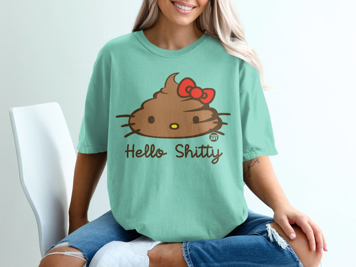 Mint green t-shirt with a smiling cartoon poop wearing a red bow and "Hello Shitty" text.
