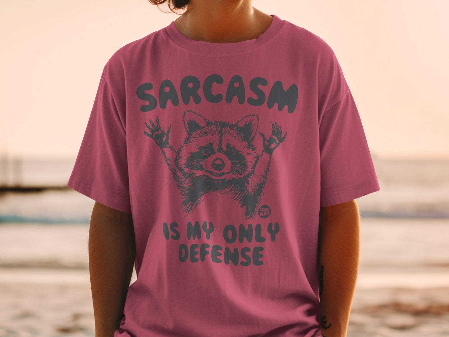 T-shirt with raccoon graphic and text "Sarcasm is my only defense."