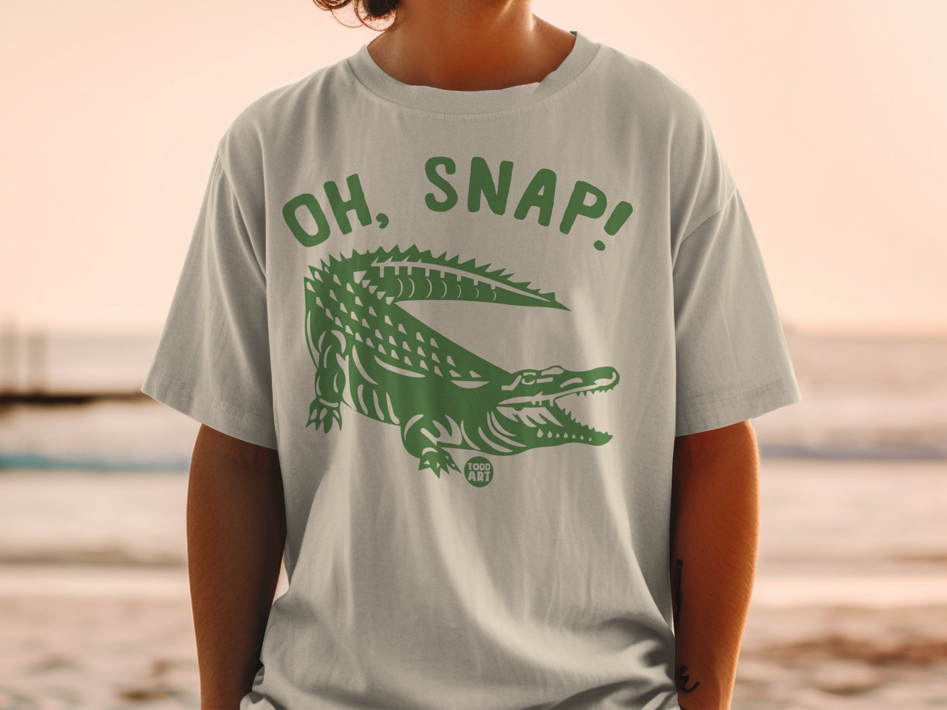 Light gray t-shirt with green alligator graphic and "OH, SNAP!" text.