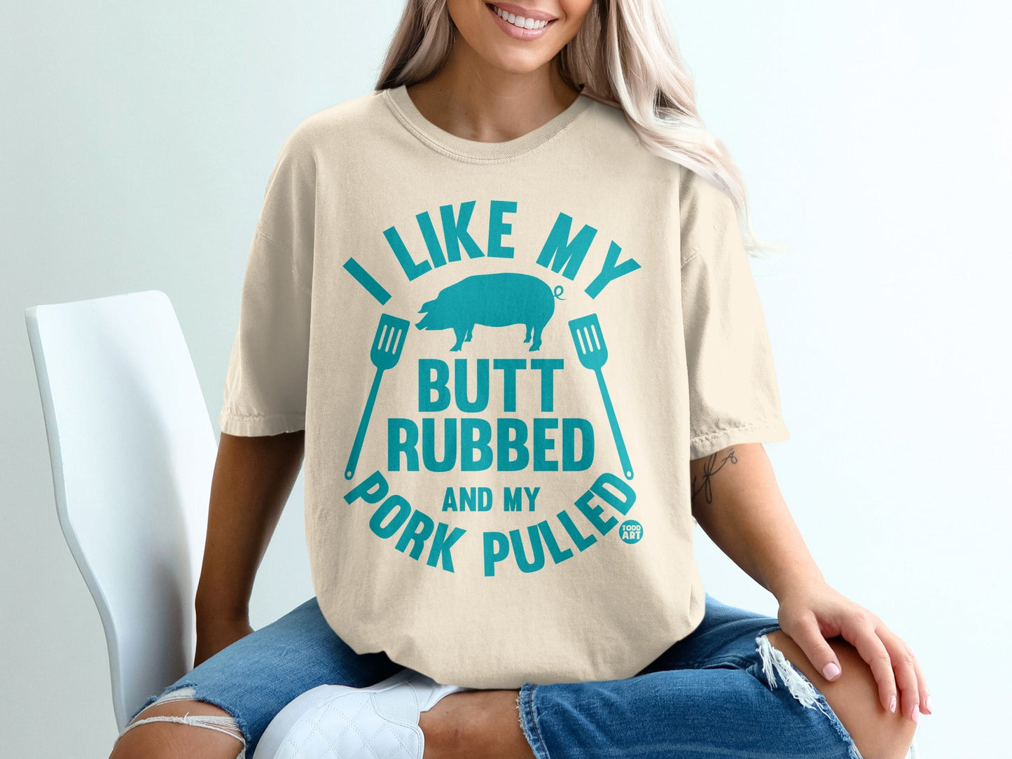 Cream t-shirt with blue text and pig graphic: "I like my butt rubbed and my pork pulled."