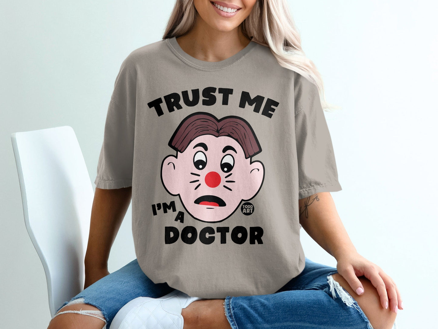 Gray t-shirt with "TRUST ME I'M A DOCTOR" text and cartoon face.