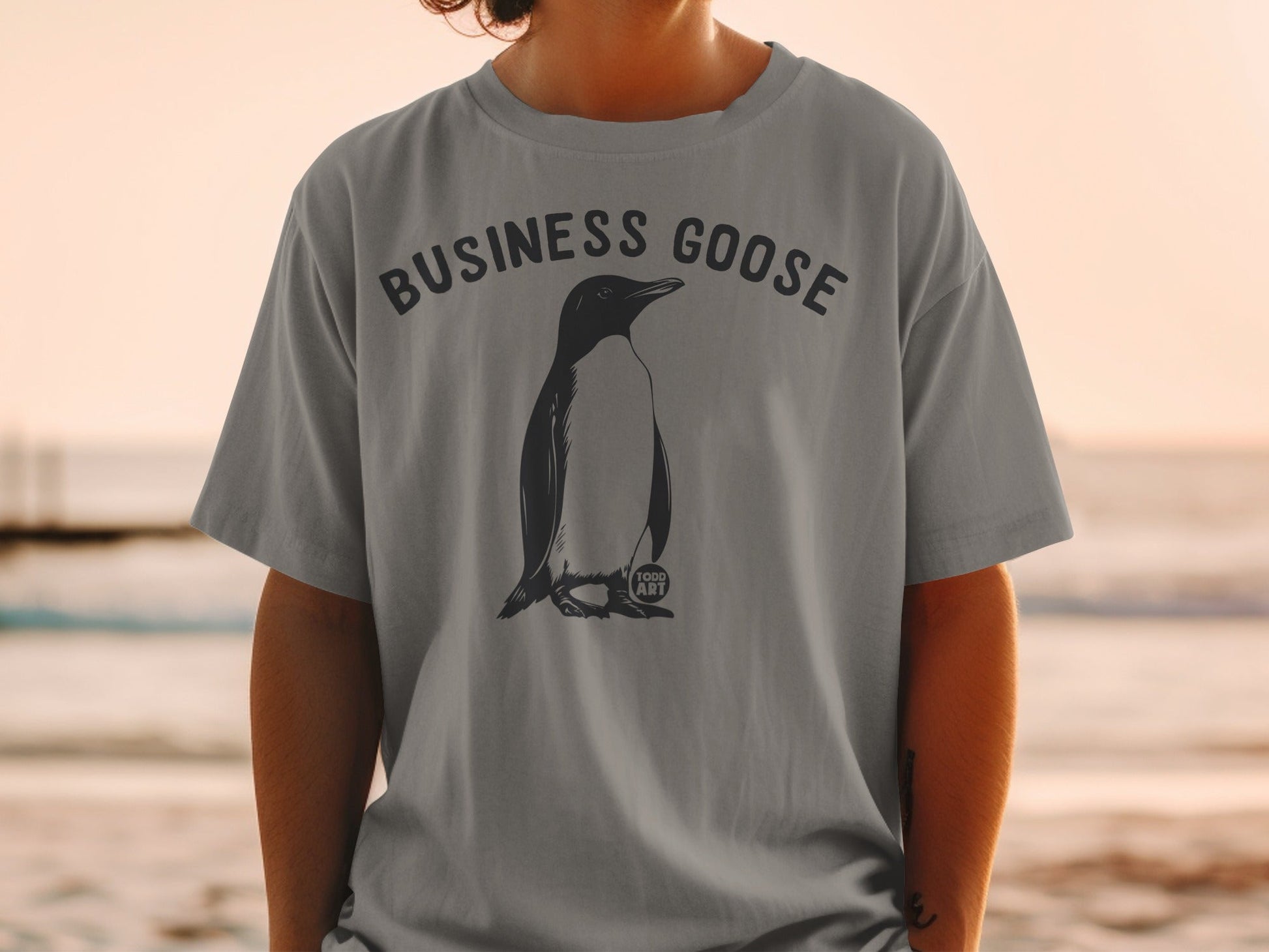 Grey t-shirt with a black penguin illustration and "BUSINESS GOOSE" text.