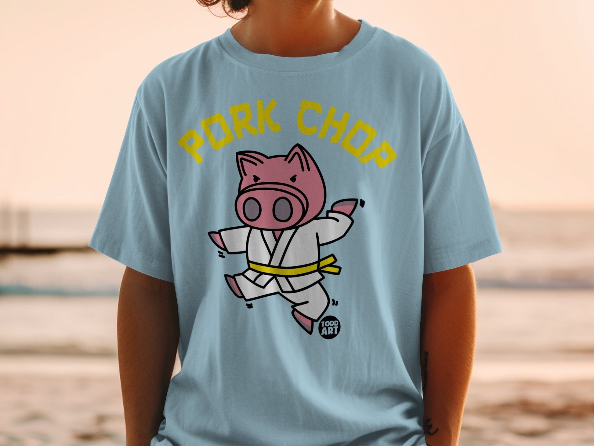 Cartoon pig in a yellow-belted gi with "PORK CHOP" text.