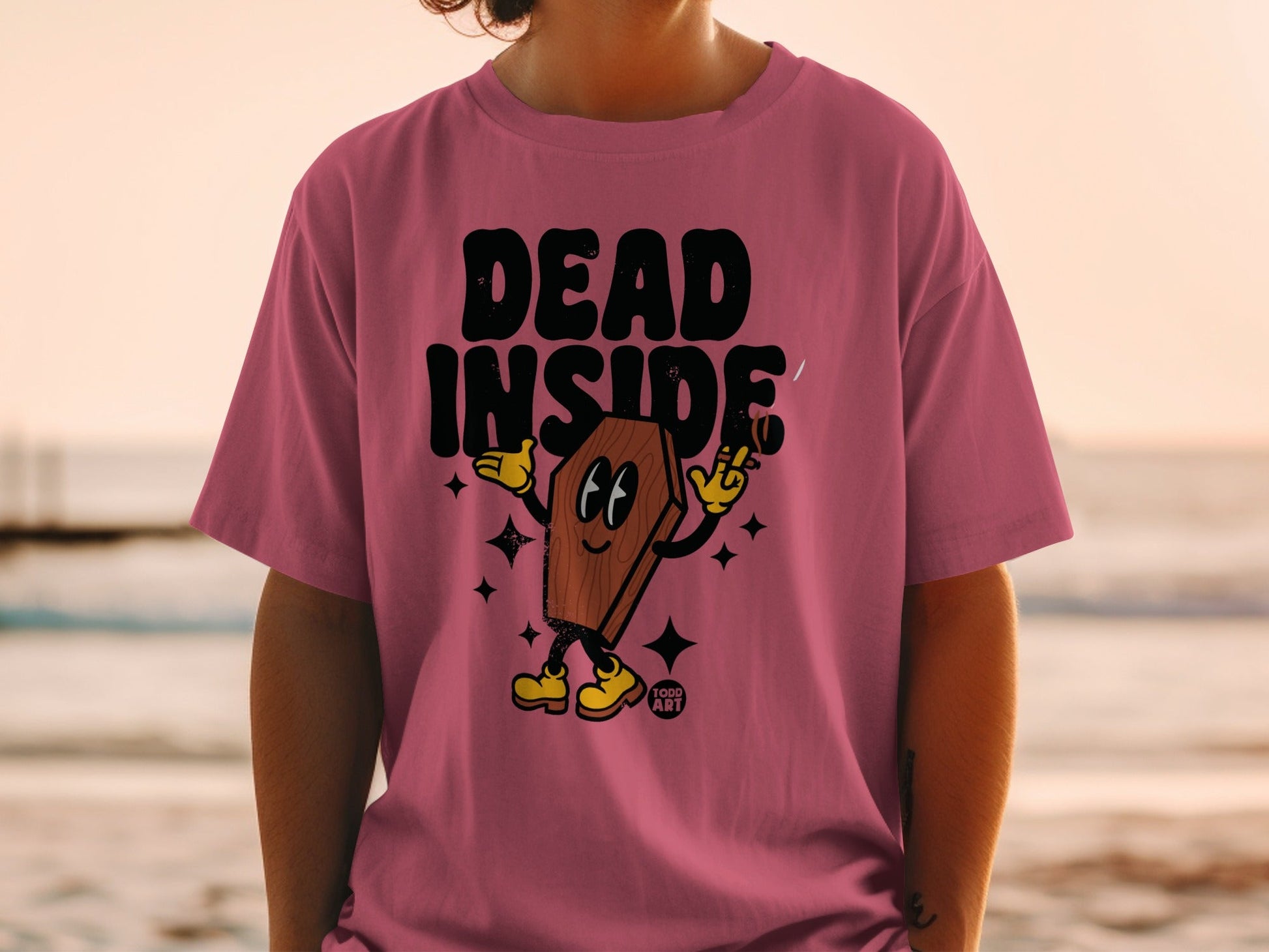 Pink t-shirt with coffin character saying "DEAD INSIDE" and holding a cigarette.