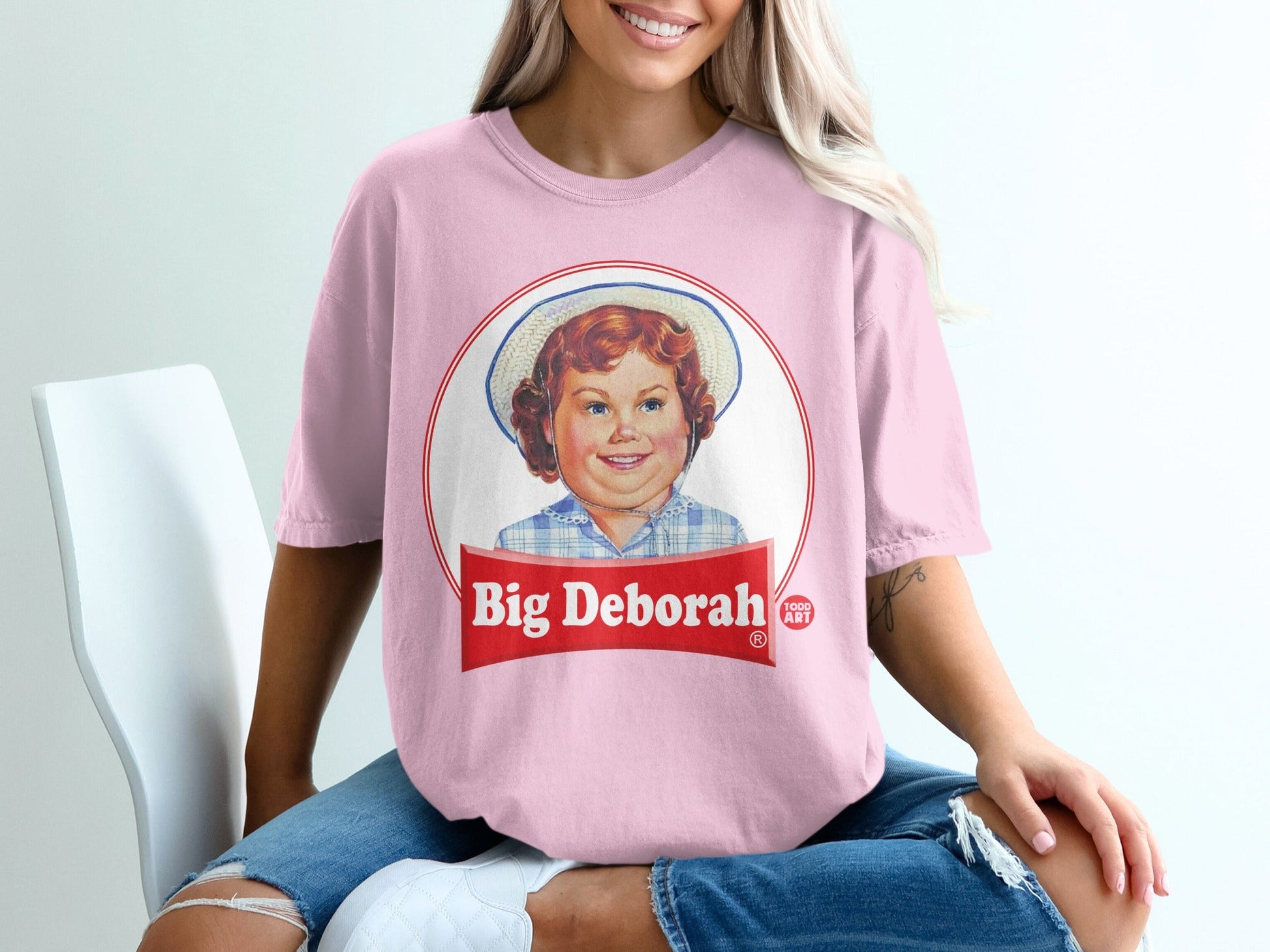 Pink t-shirt with "Big Deborah" logo featuring a smiling child in a hat.