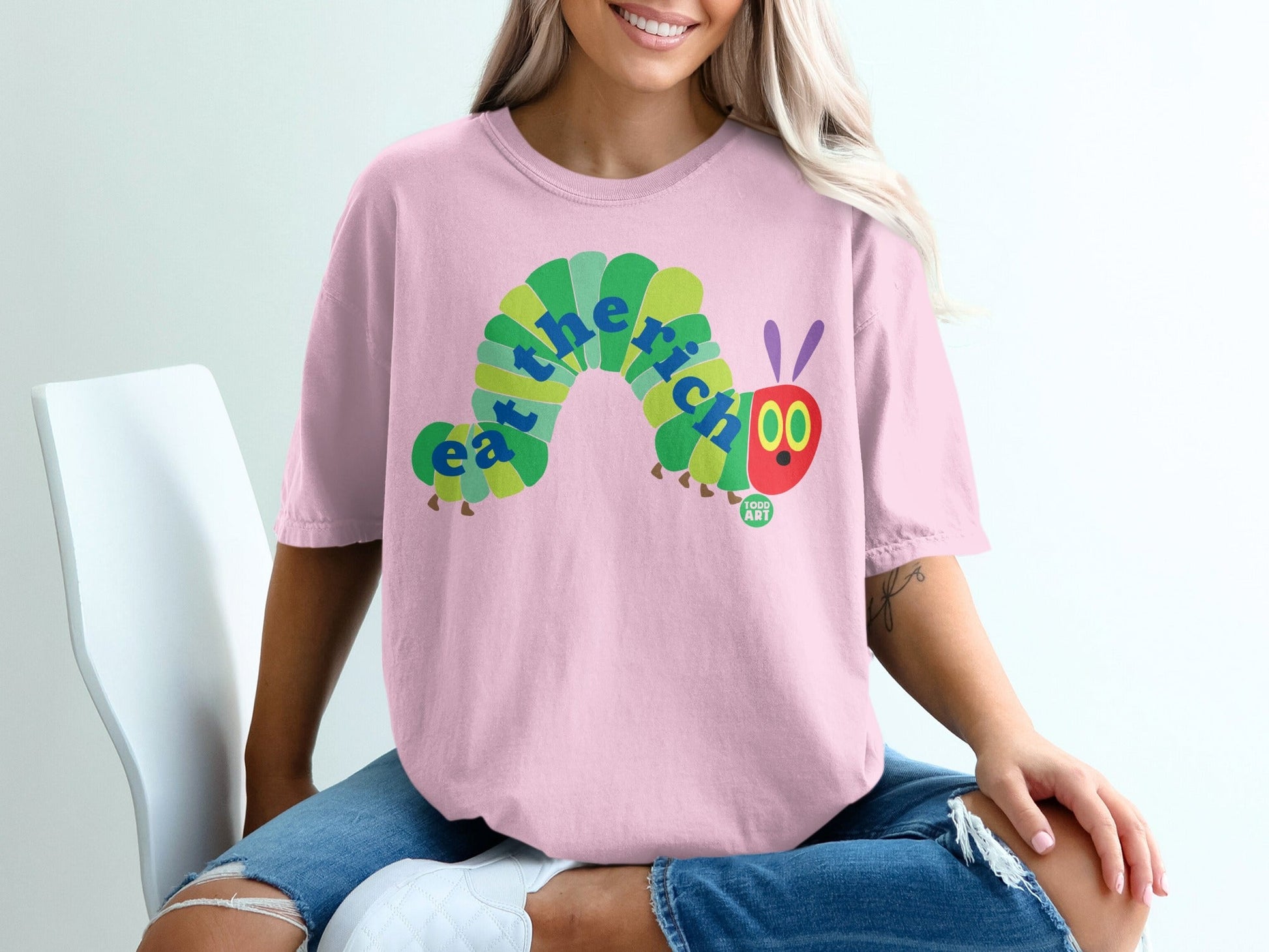 Pink t-shirt with "eat the rich" caterpillar graphic.