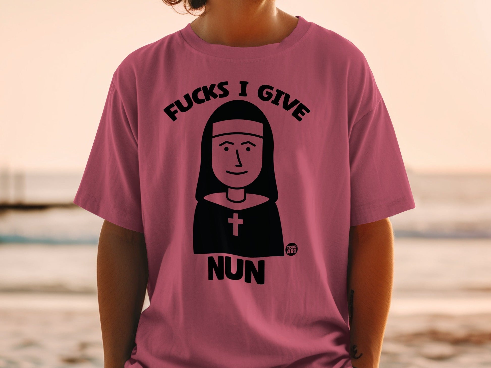 Pink t-shirt with "Fucks I Give NUN" text and nun graphic.