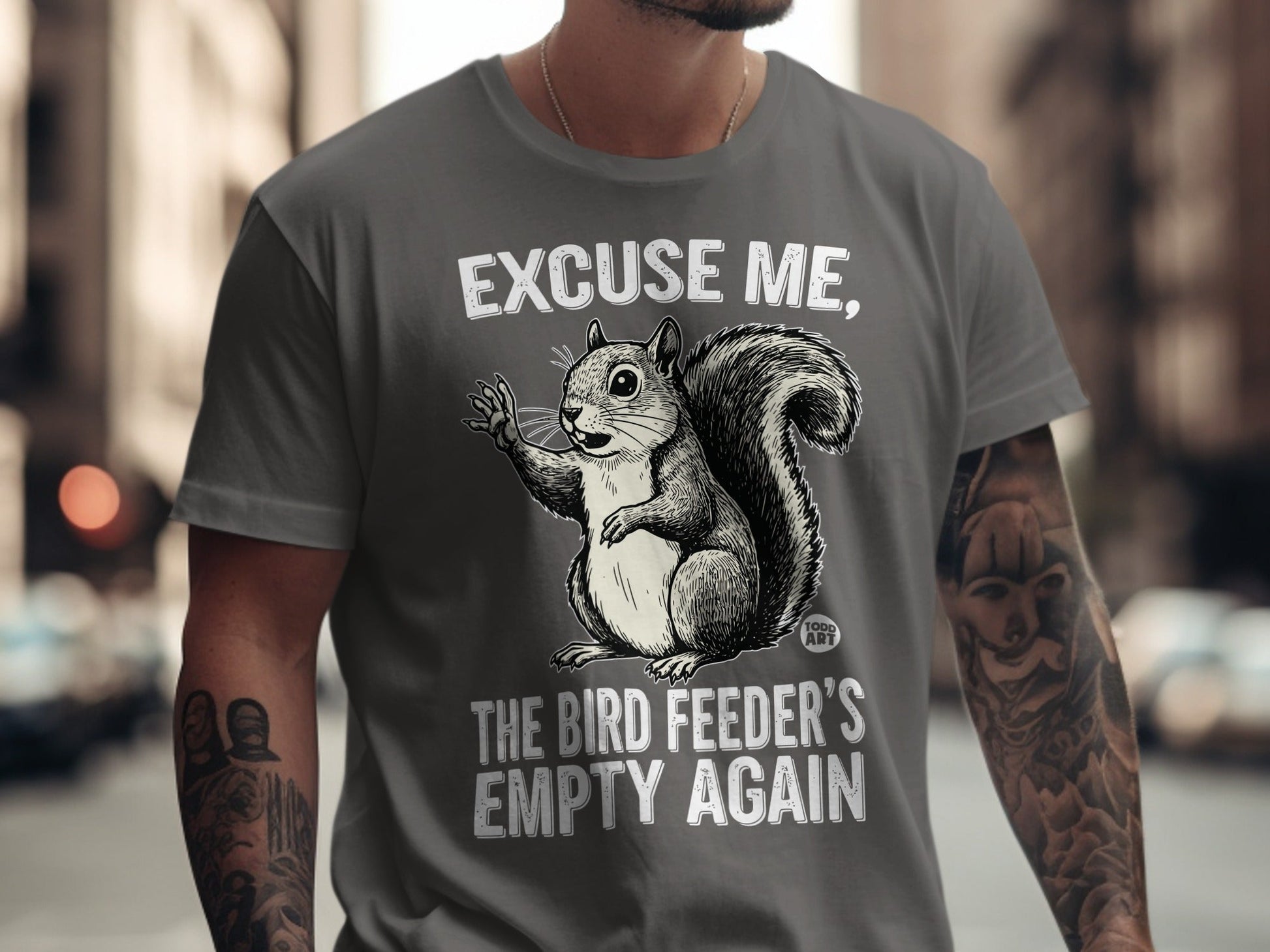 Gray t-shirt with a squirrel saying "Excuse me, the bird feeder's empty again".